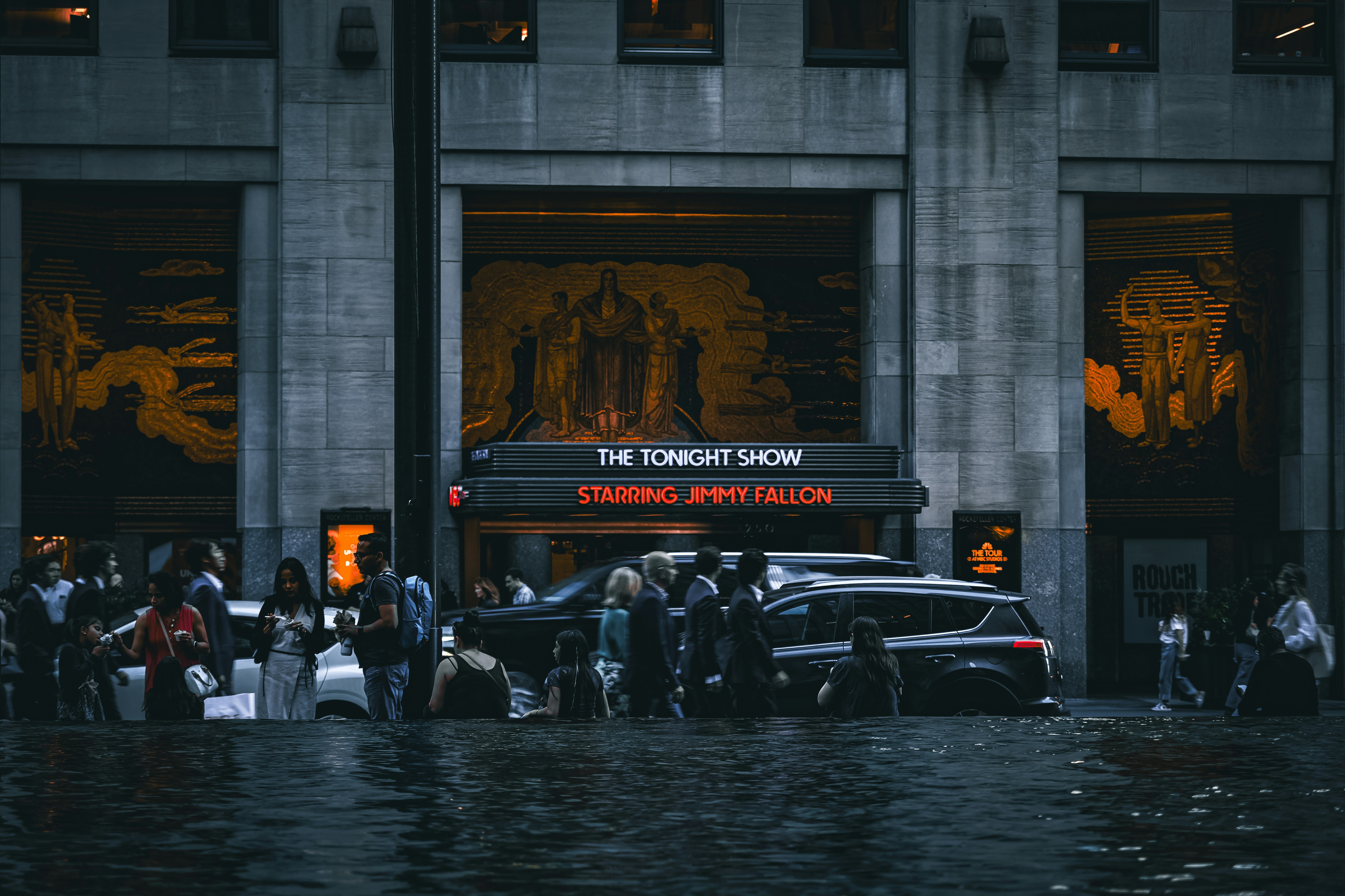 People and cars in flooded street outside building