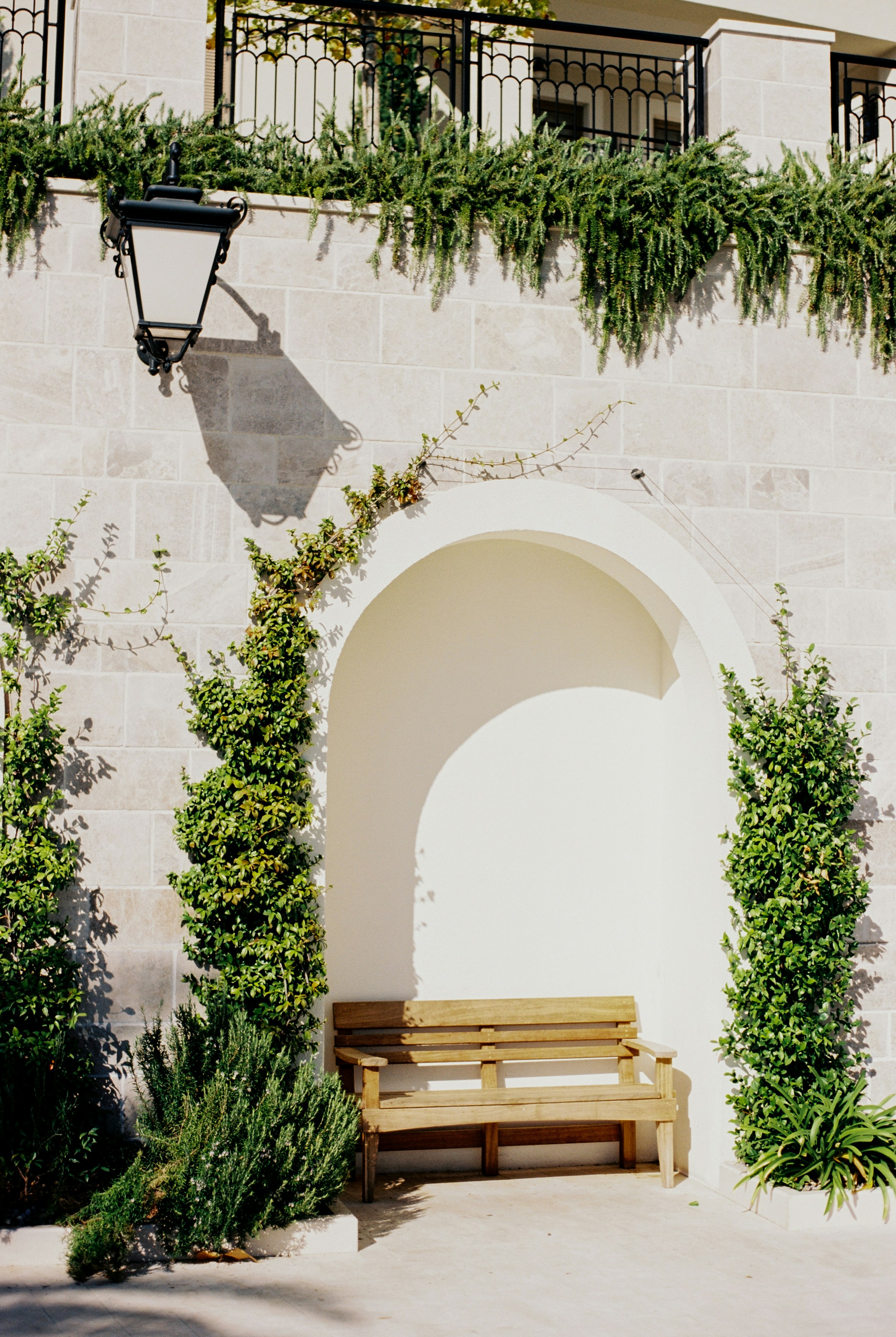 Wooden bench in an arched alcove with greenery.