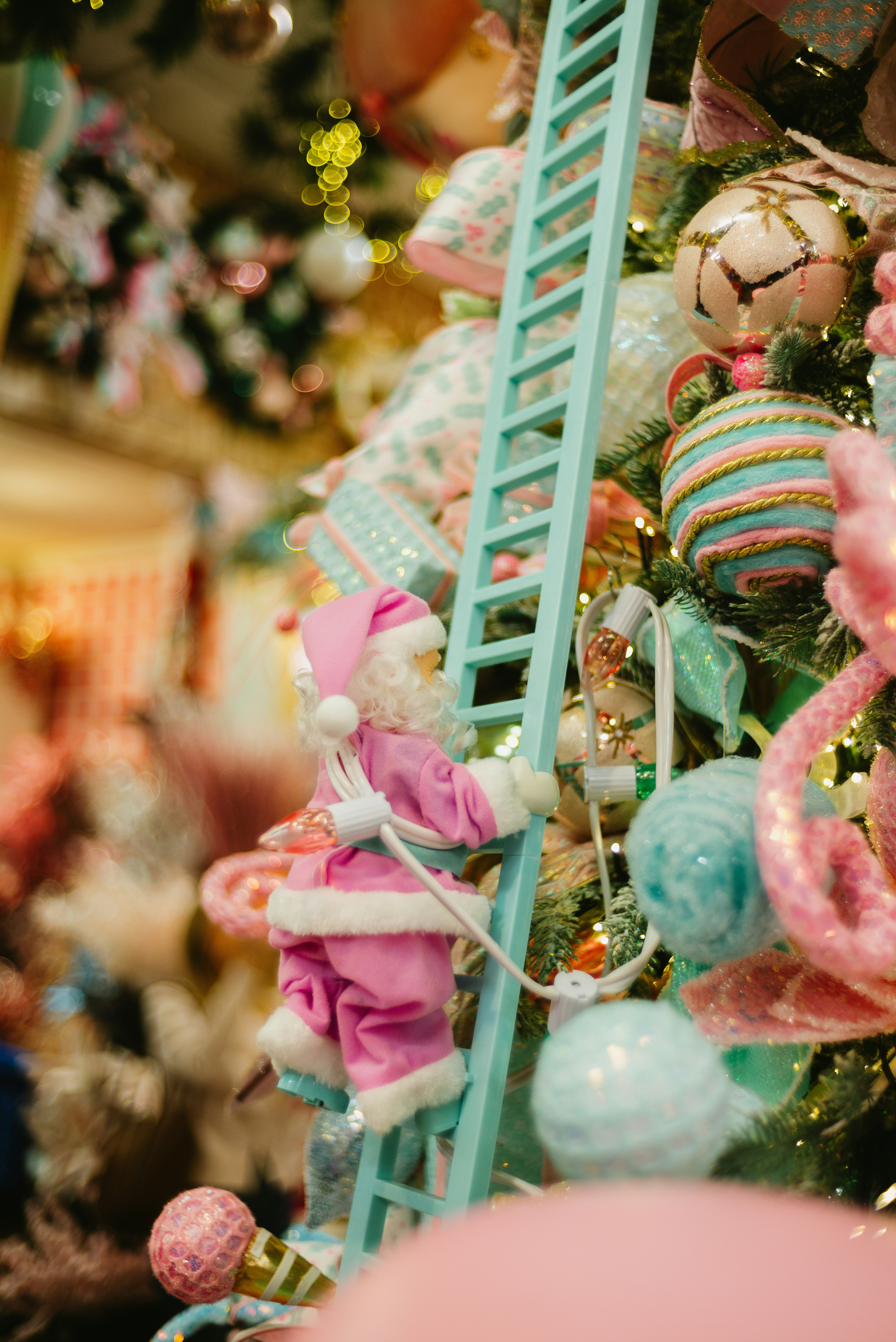 Santa climbing a ladder on a decorated christmas tree.