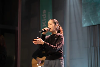 Woman singing into a microphone on stage.