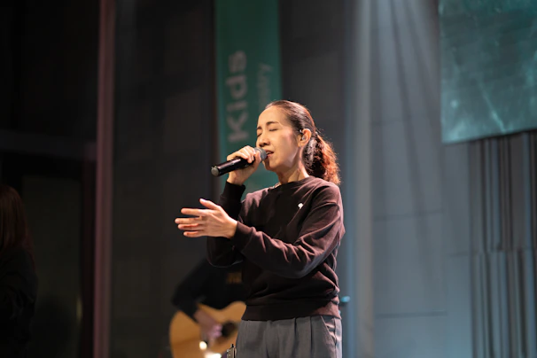 Woman singing into a microphone on stage.