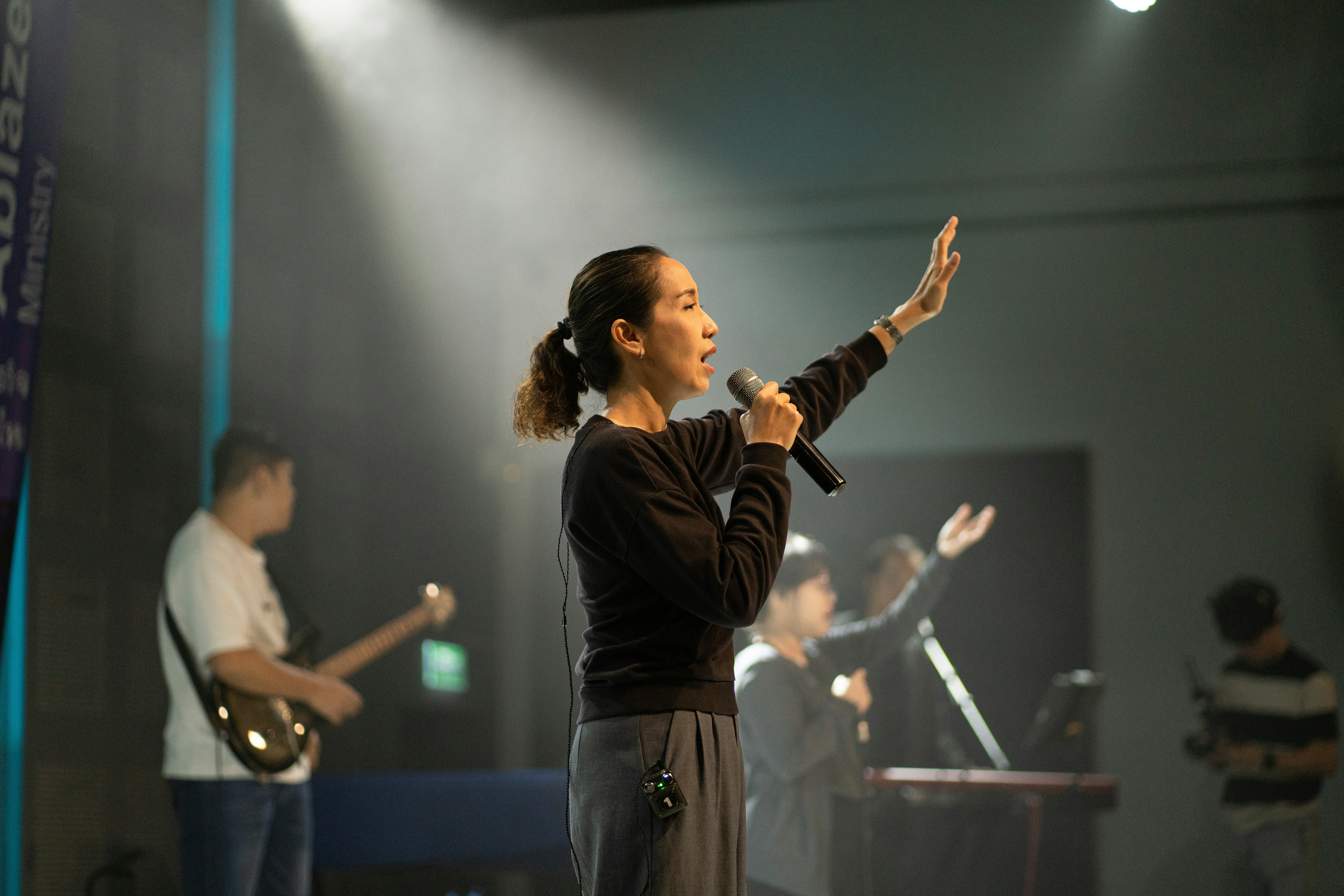 Woman singing into microphone on stage with band