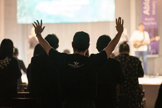 People with hands raised in worship at a worship service.