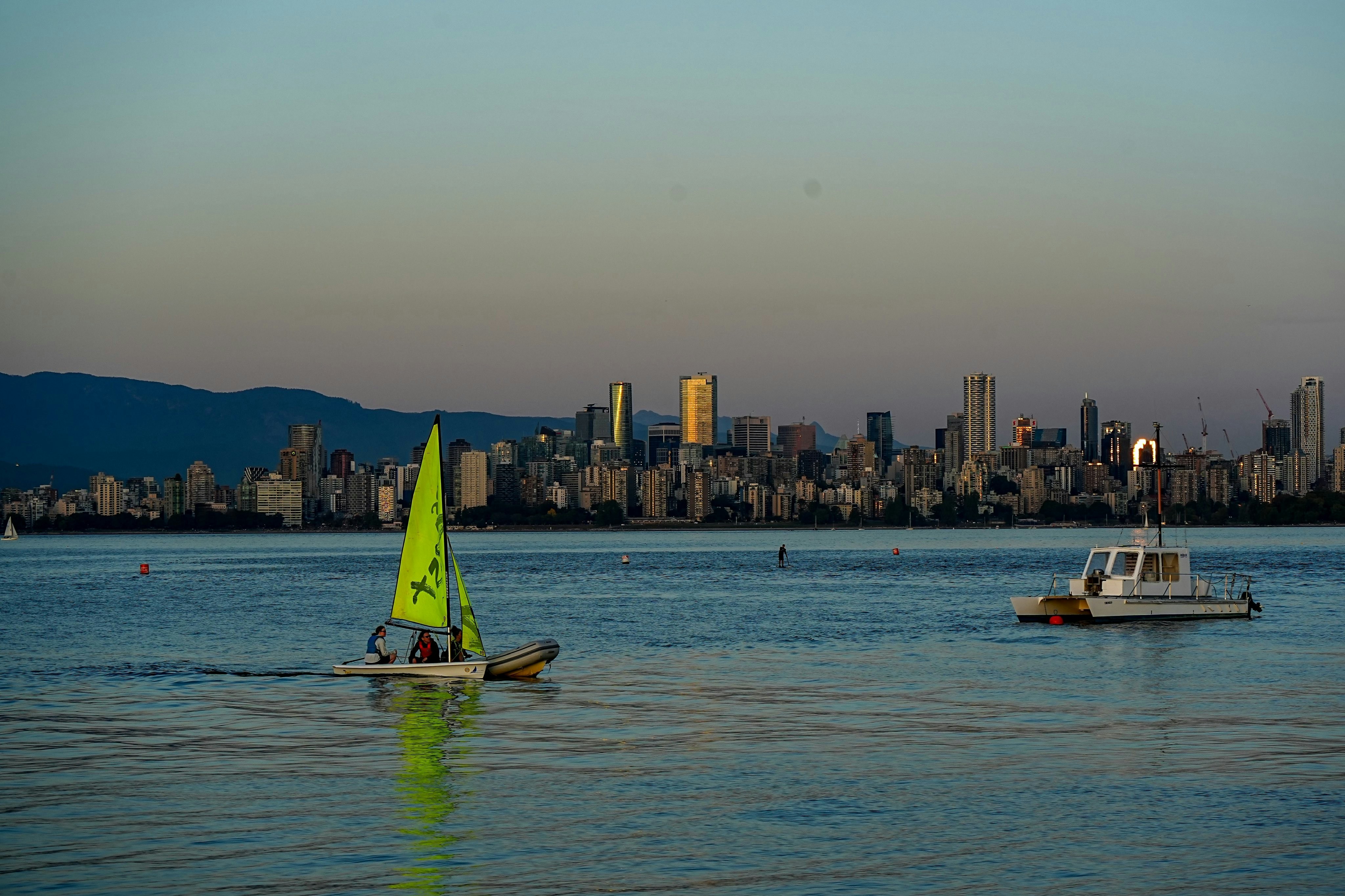 Sailboat and boat on water with city skyline