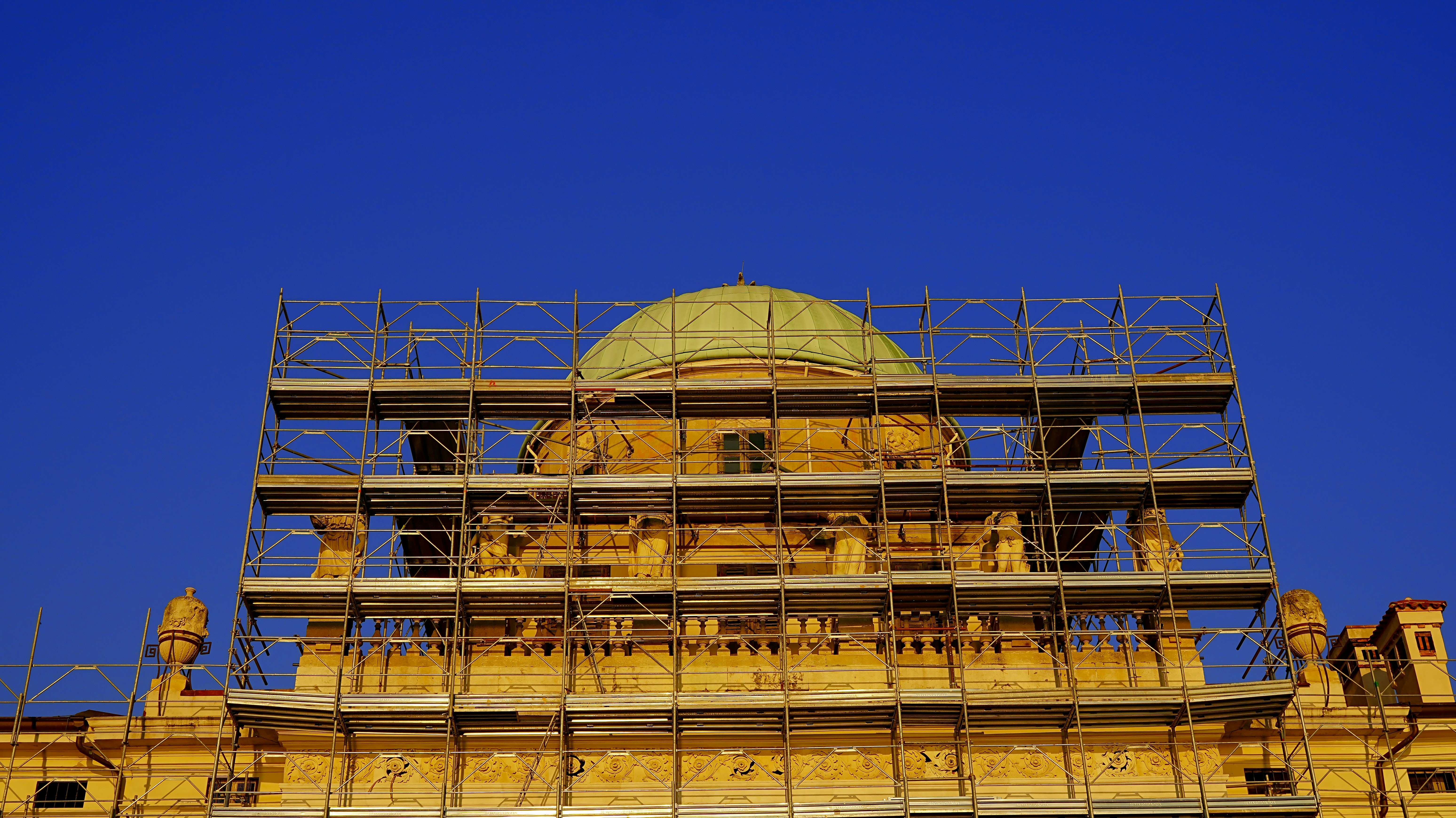 Building dome covered in scaffolding under blue sky