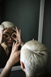 Woman looking through fingers in mirror