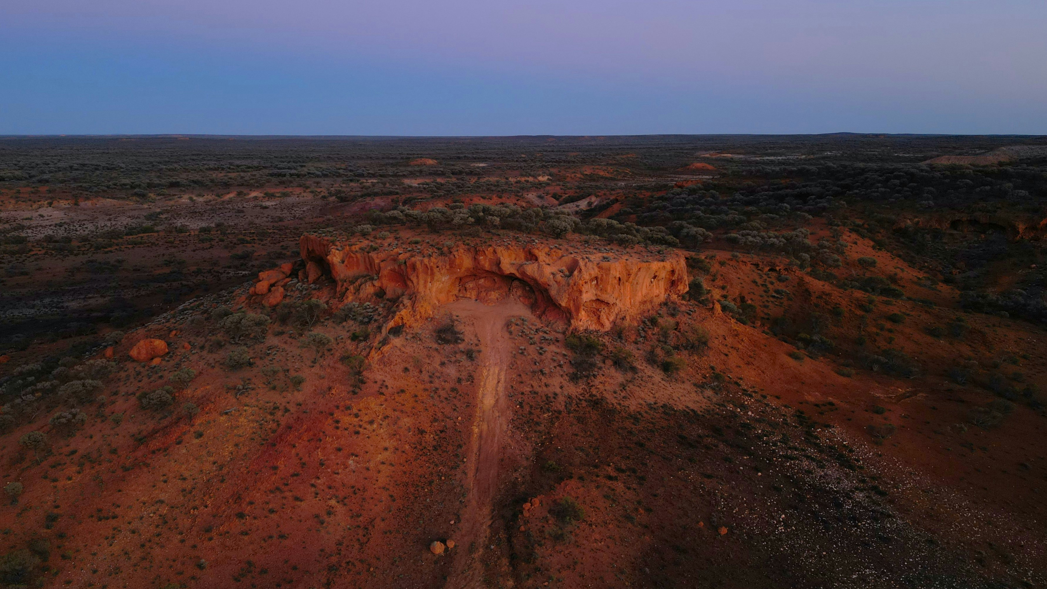 Arid landscape with rock formations at dusk.