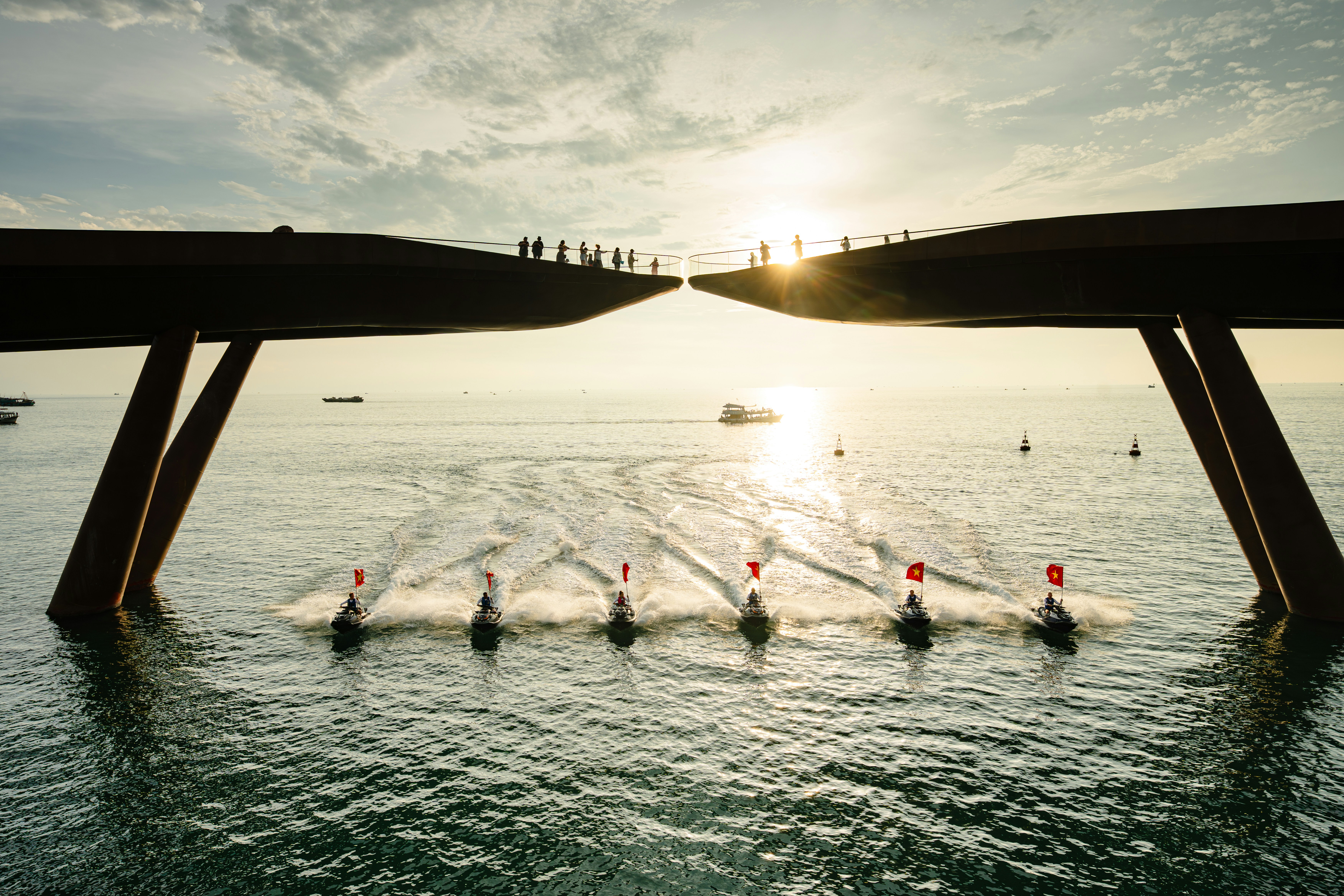 People on bridge overlooking boats racing on the ocean