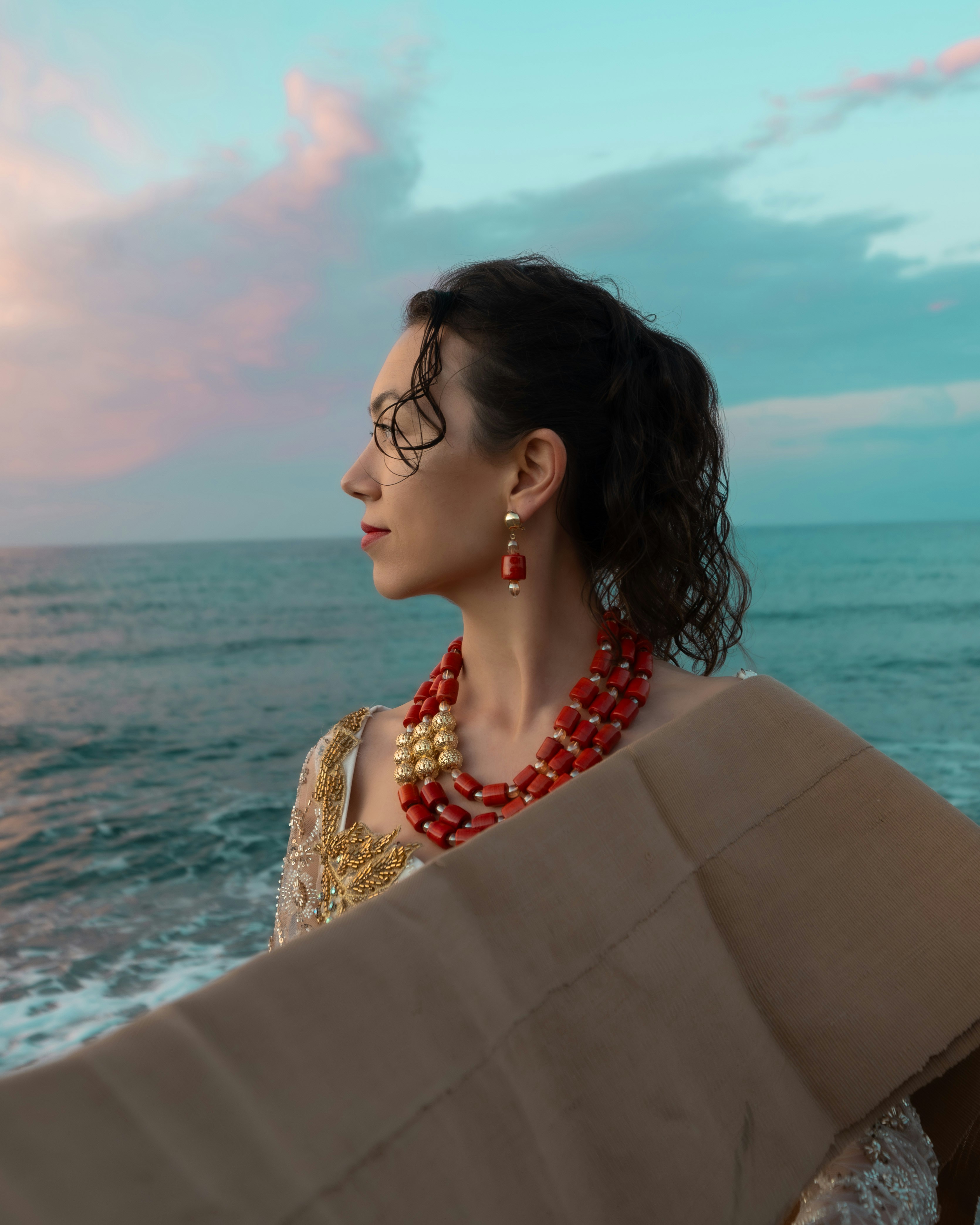 Mujer con atuendo tradicional junto al mar al atardecer