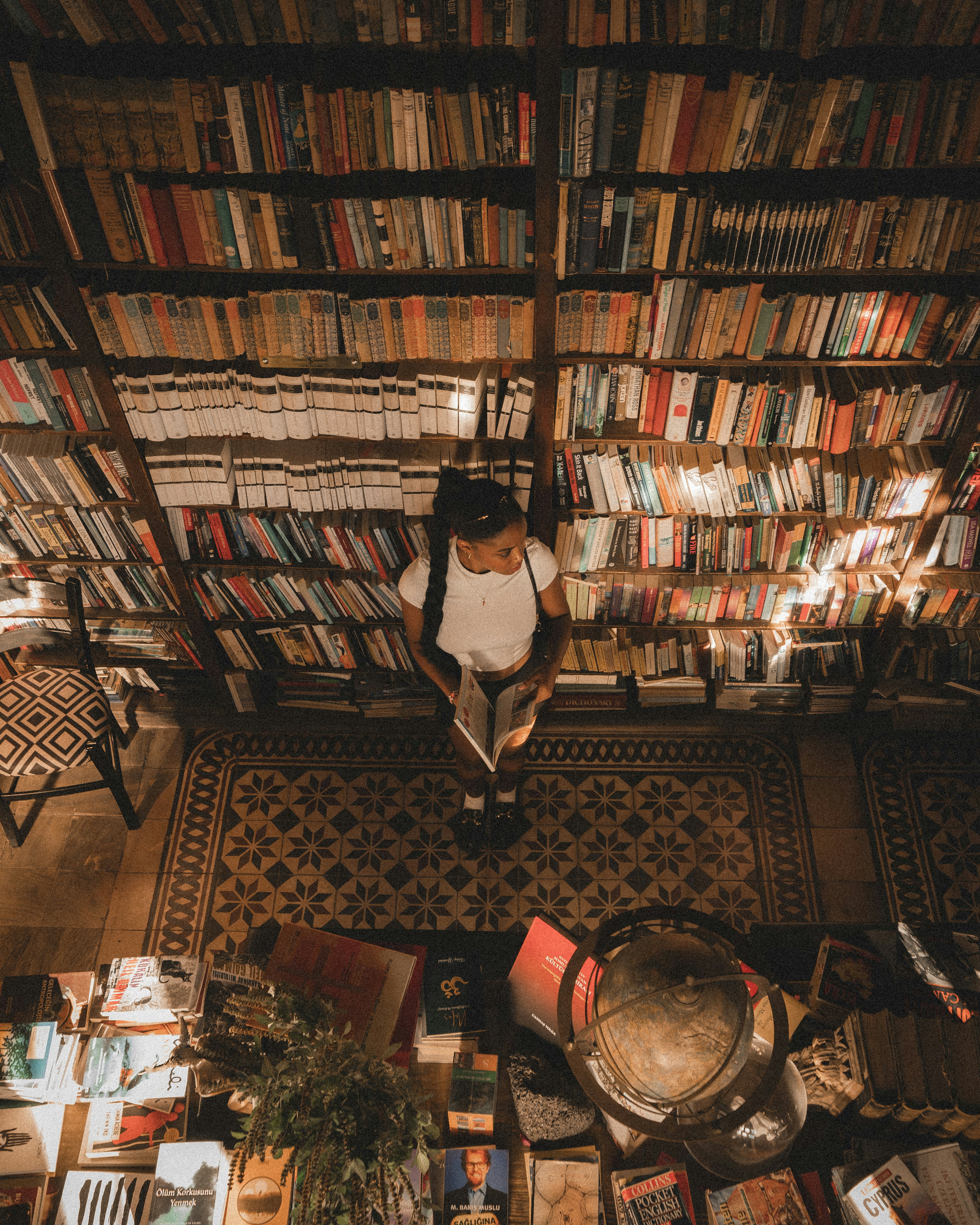 Person reading a book in a library full of books.