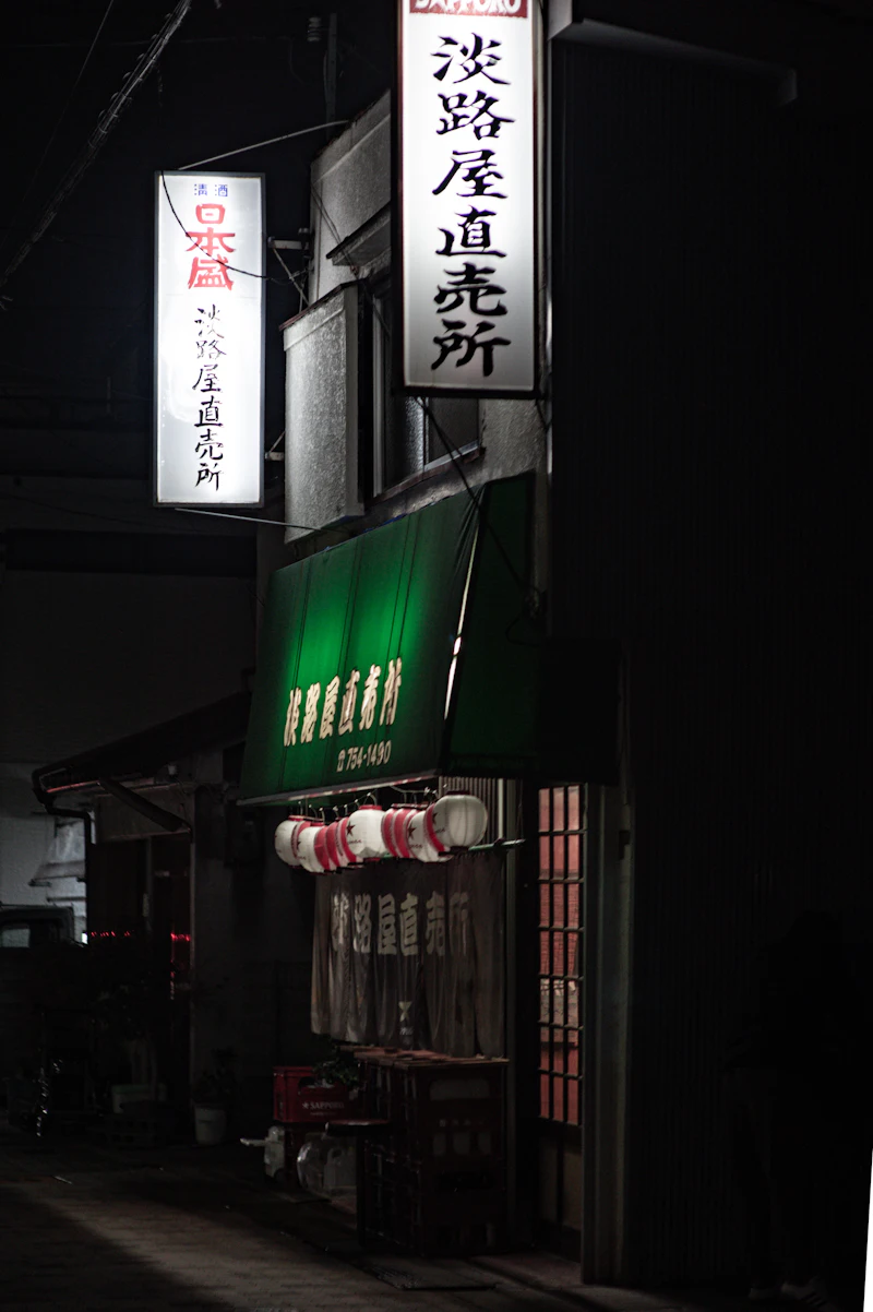 夜の外観。提灯と暖簾に灯りがともる居酒屋の入口