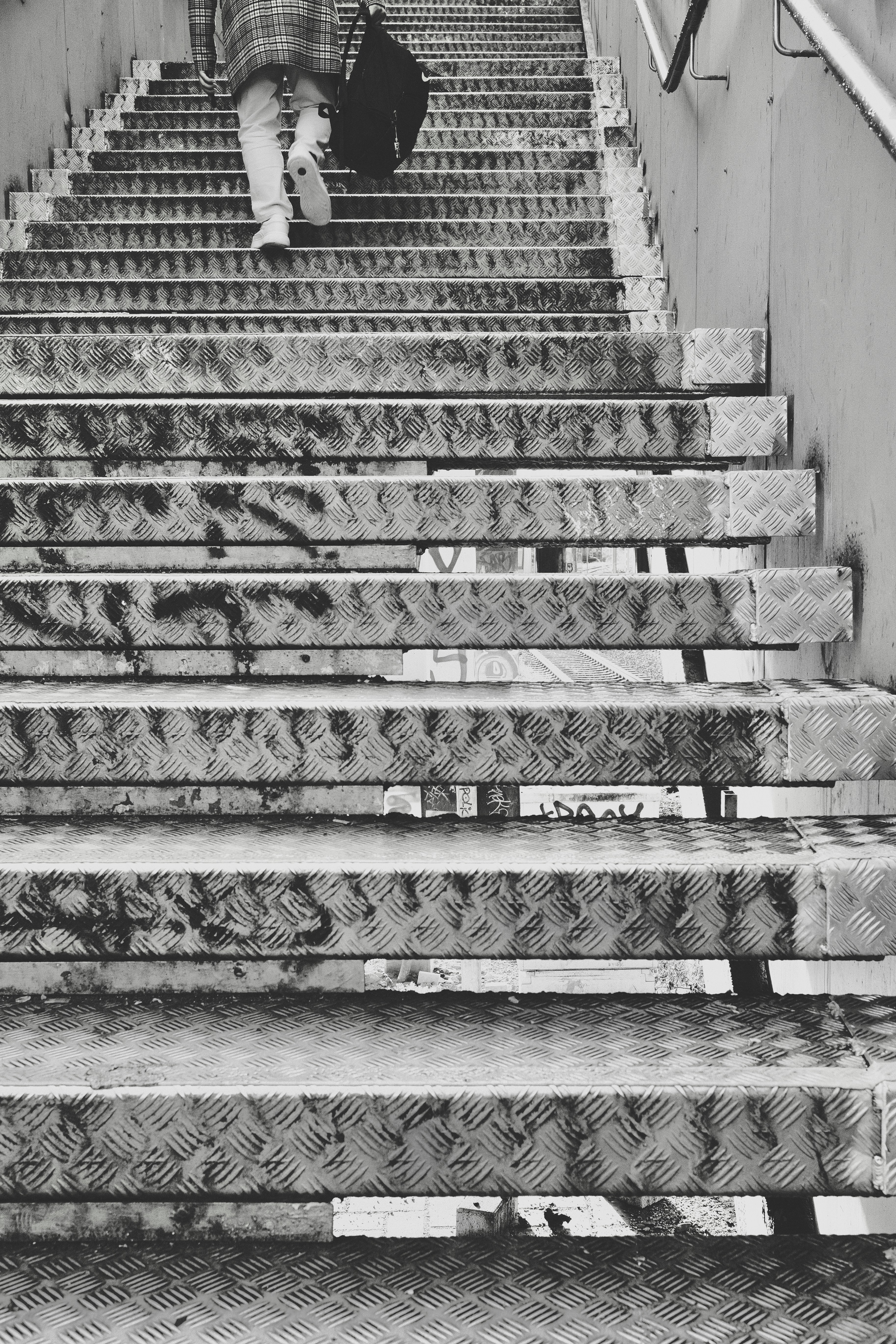 Person walking up metal stairs with diamond plate treads