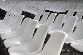 Rows of empty white plastic chairs indoors.