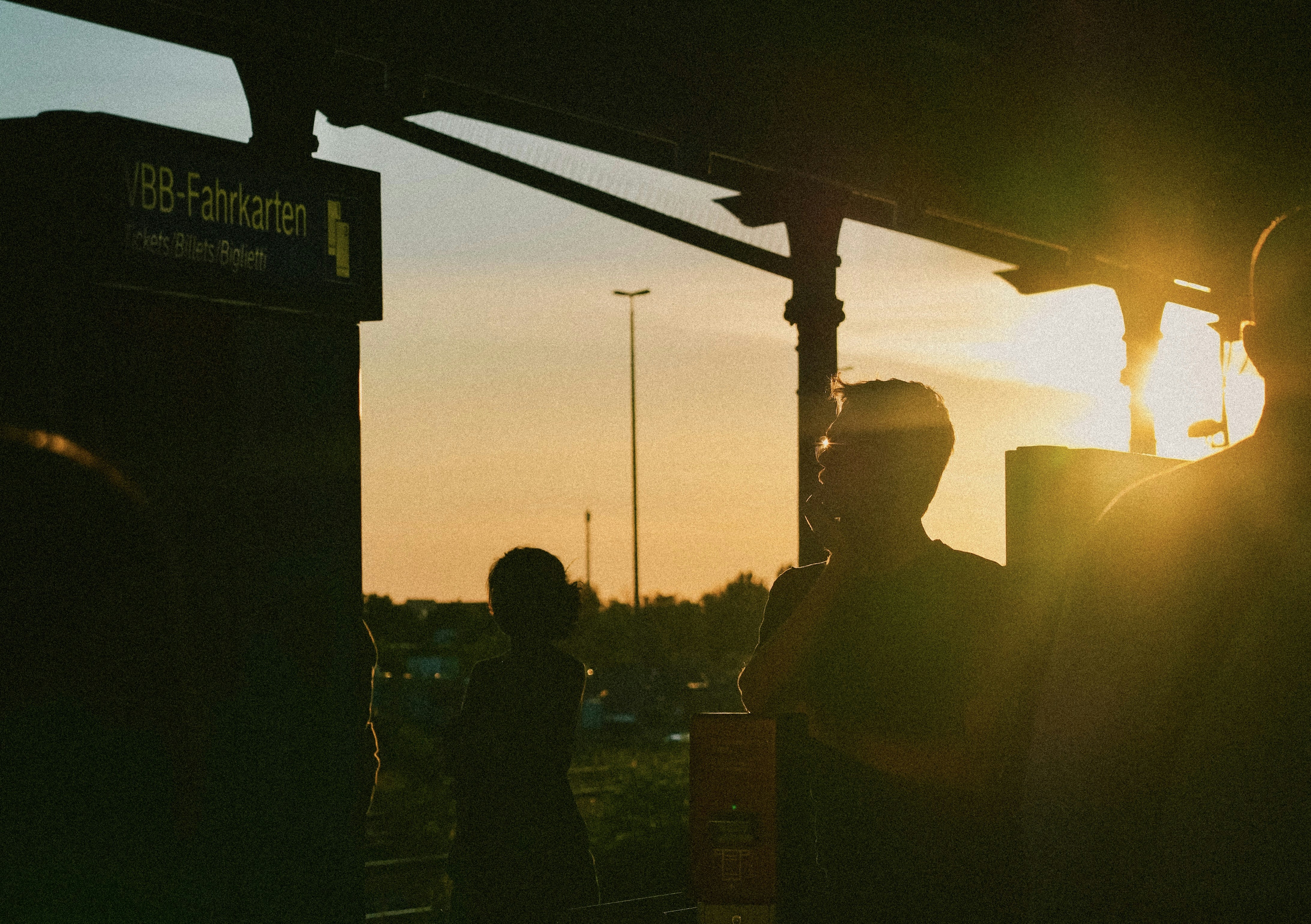 夕暮れ時の駅にいる人々のシルエット。