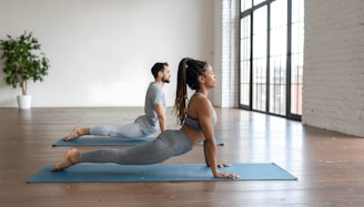 Man and woman doing upward-facing dog yoga pose.