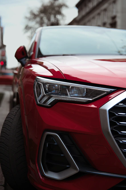 Close-up of a red car's front headlight detail