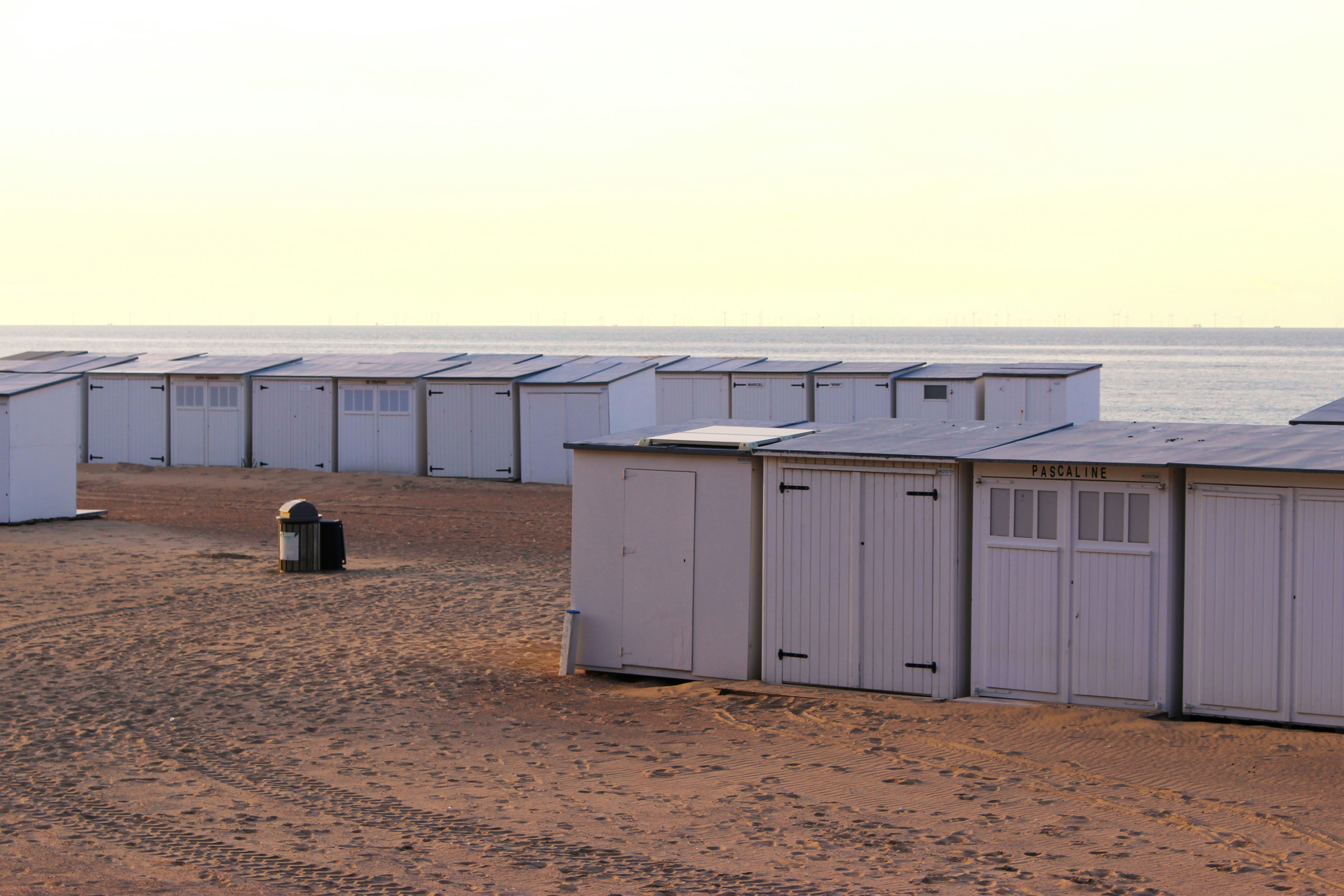 Row of white beach huts on sandy shore