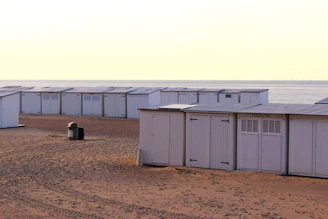 Row of white beach huts on sandy shore