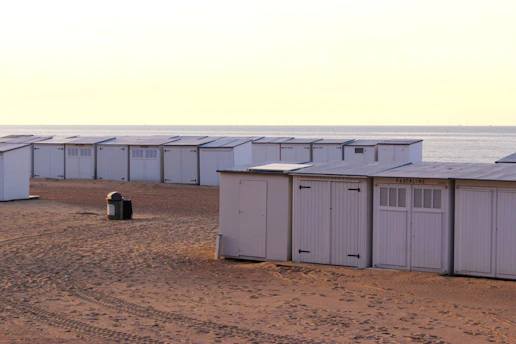 Row of white beach huts on sandy shore