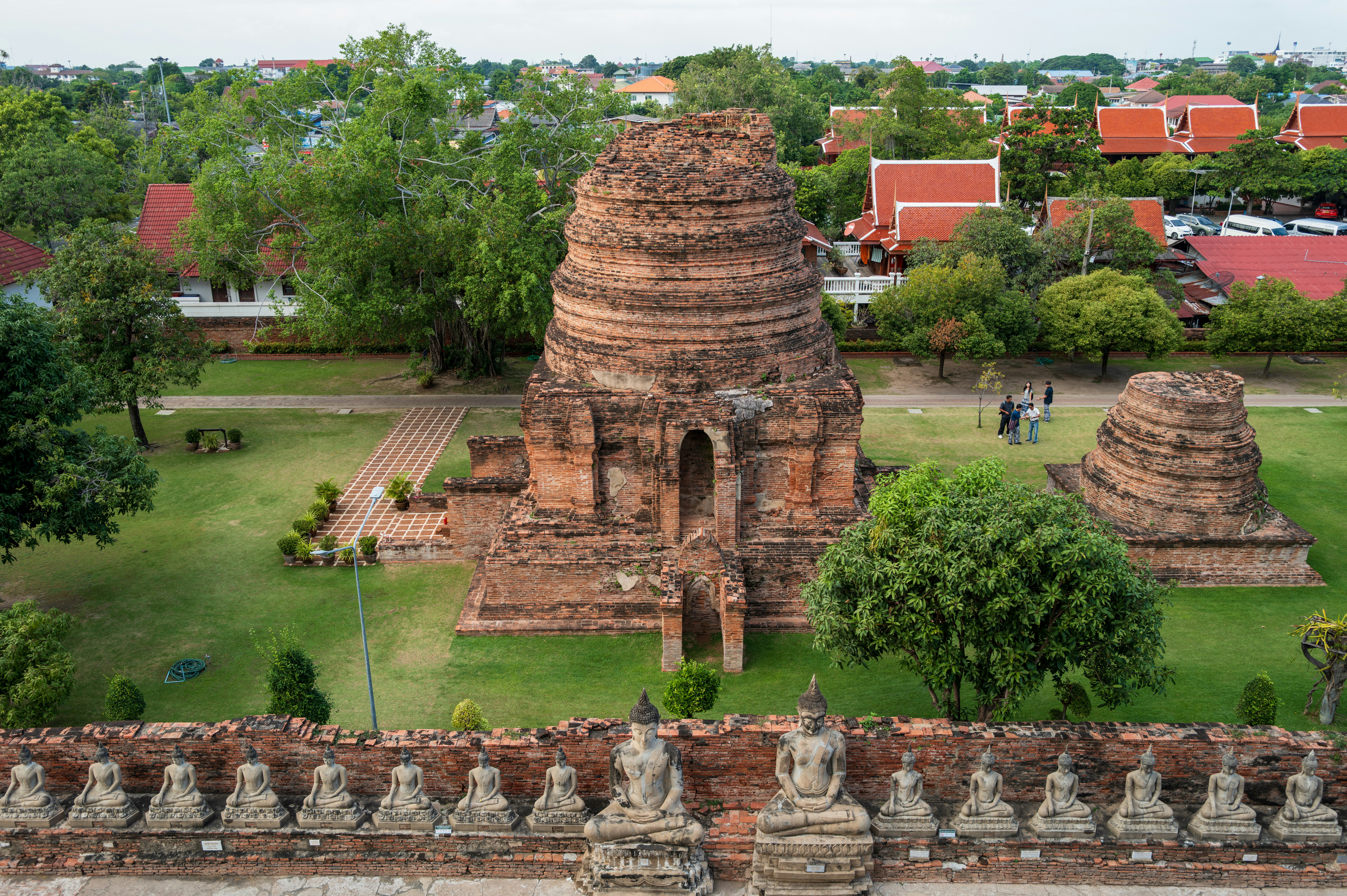 Ancient brick temple ruins with surrounding greenery and buildings.