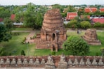 Ancient brick temple ruins with surrounding greenery and buildings.