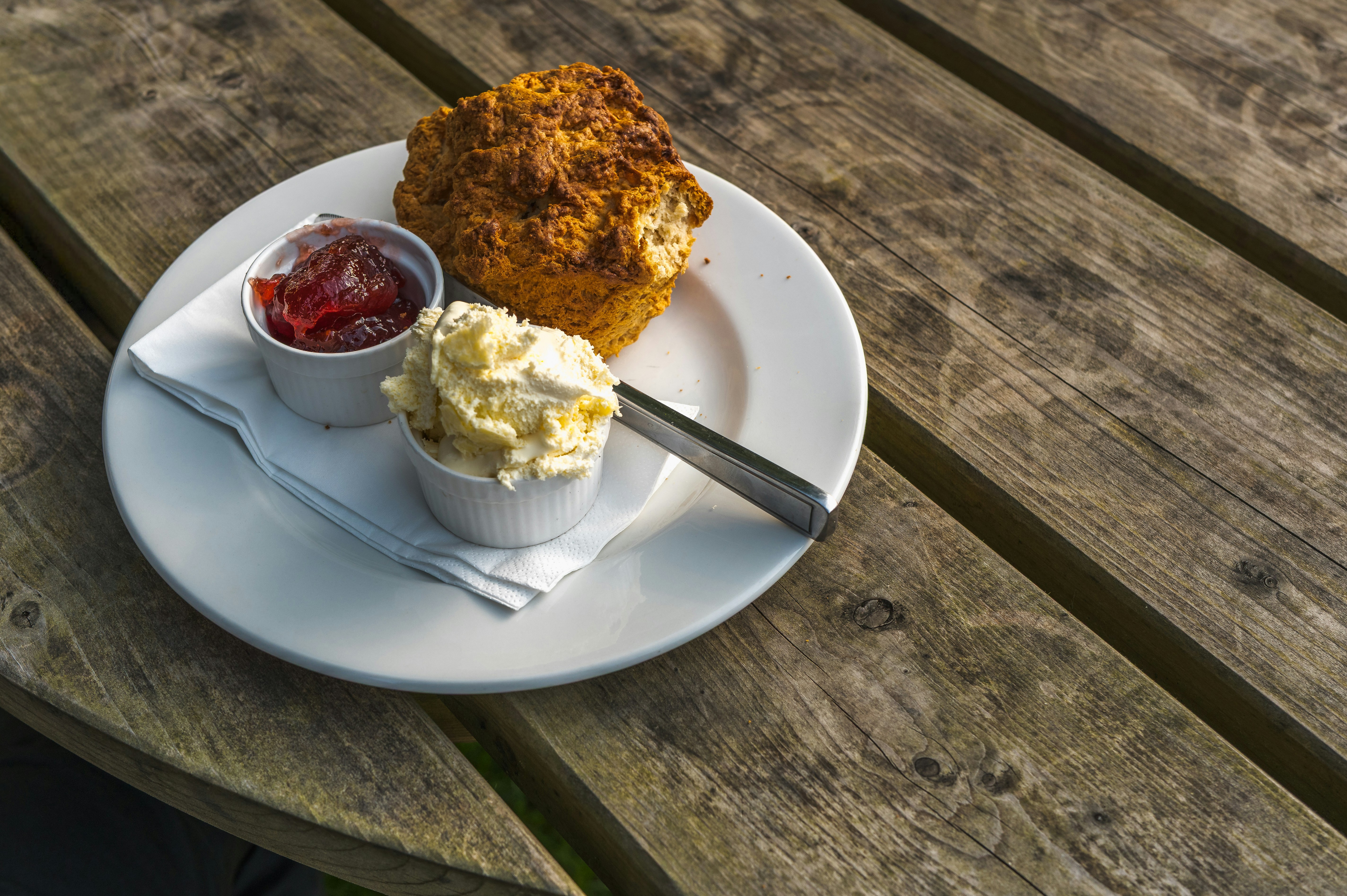 Scone with jam and cream on a wooden table