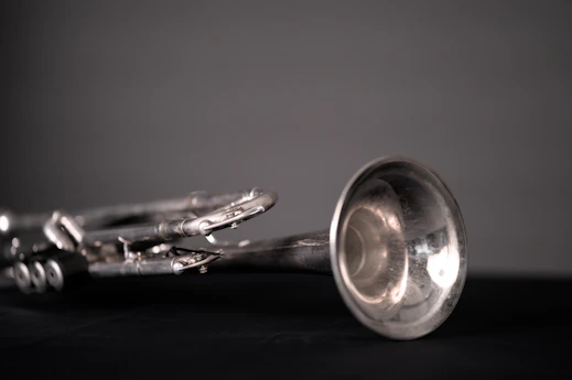 A silver trumpet lies on a dark surface.