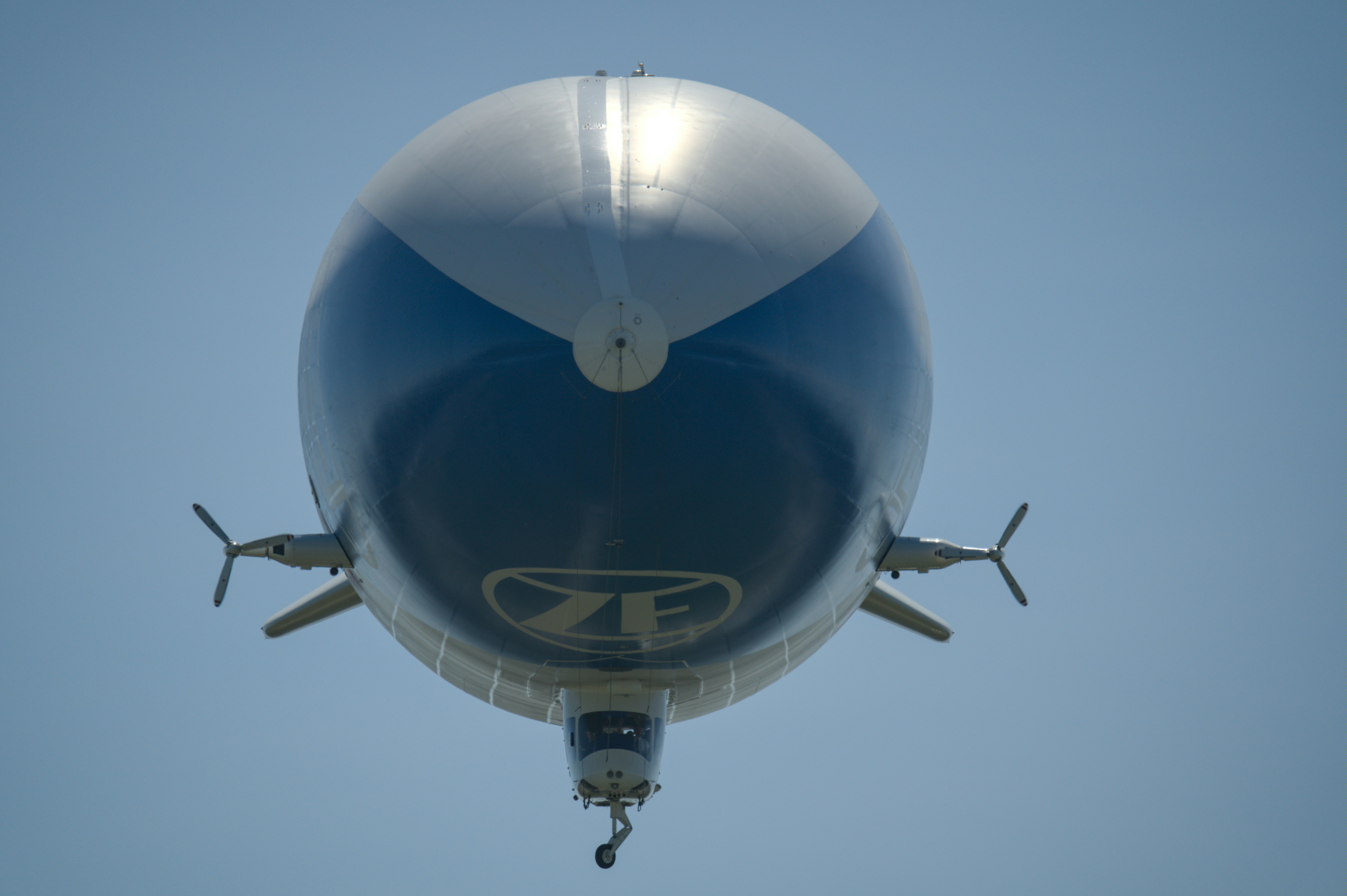 A blimp with a blue and silver body flies.