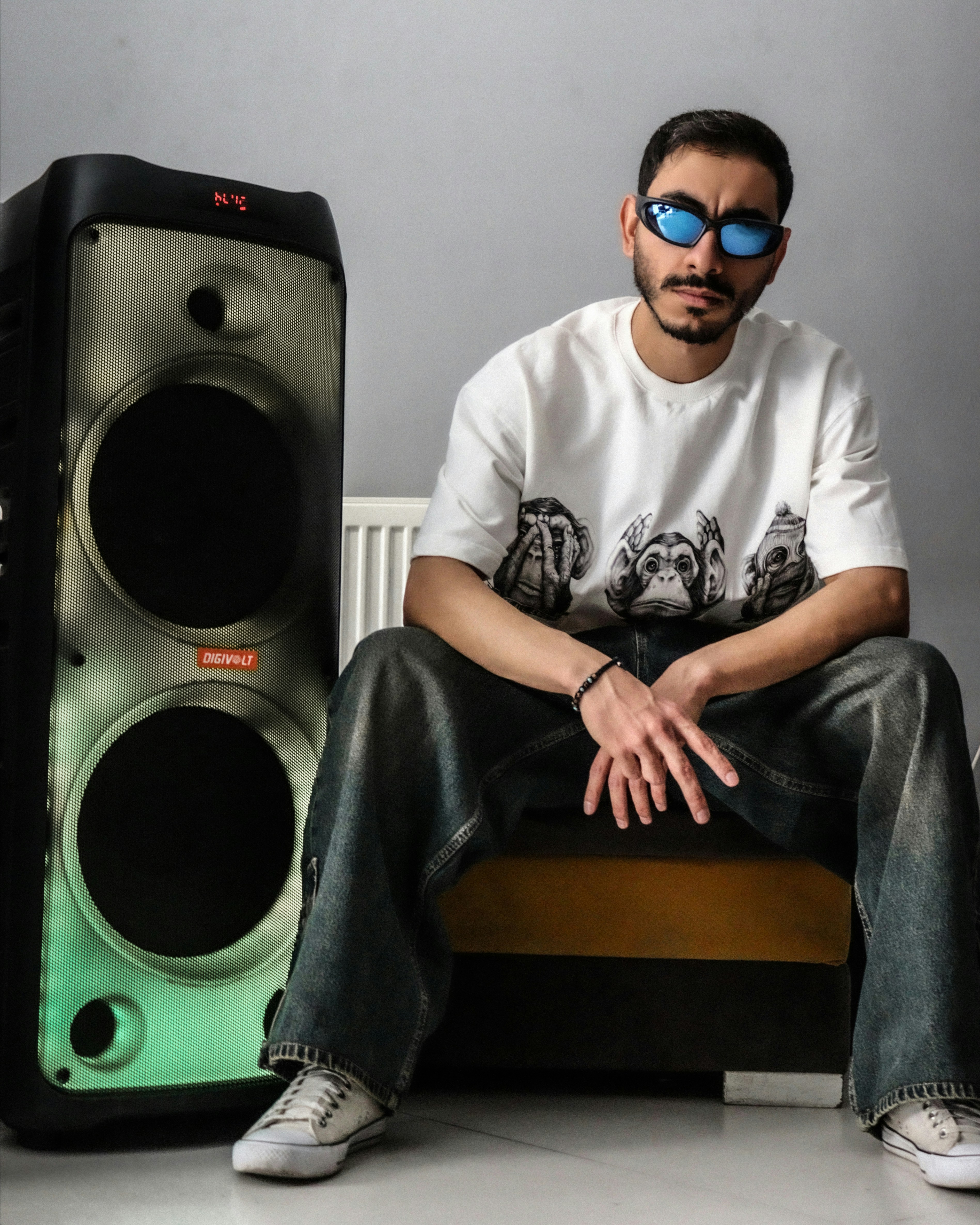 Man in sunglasses sits next to large speaker