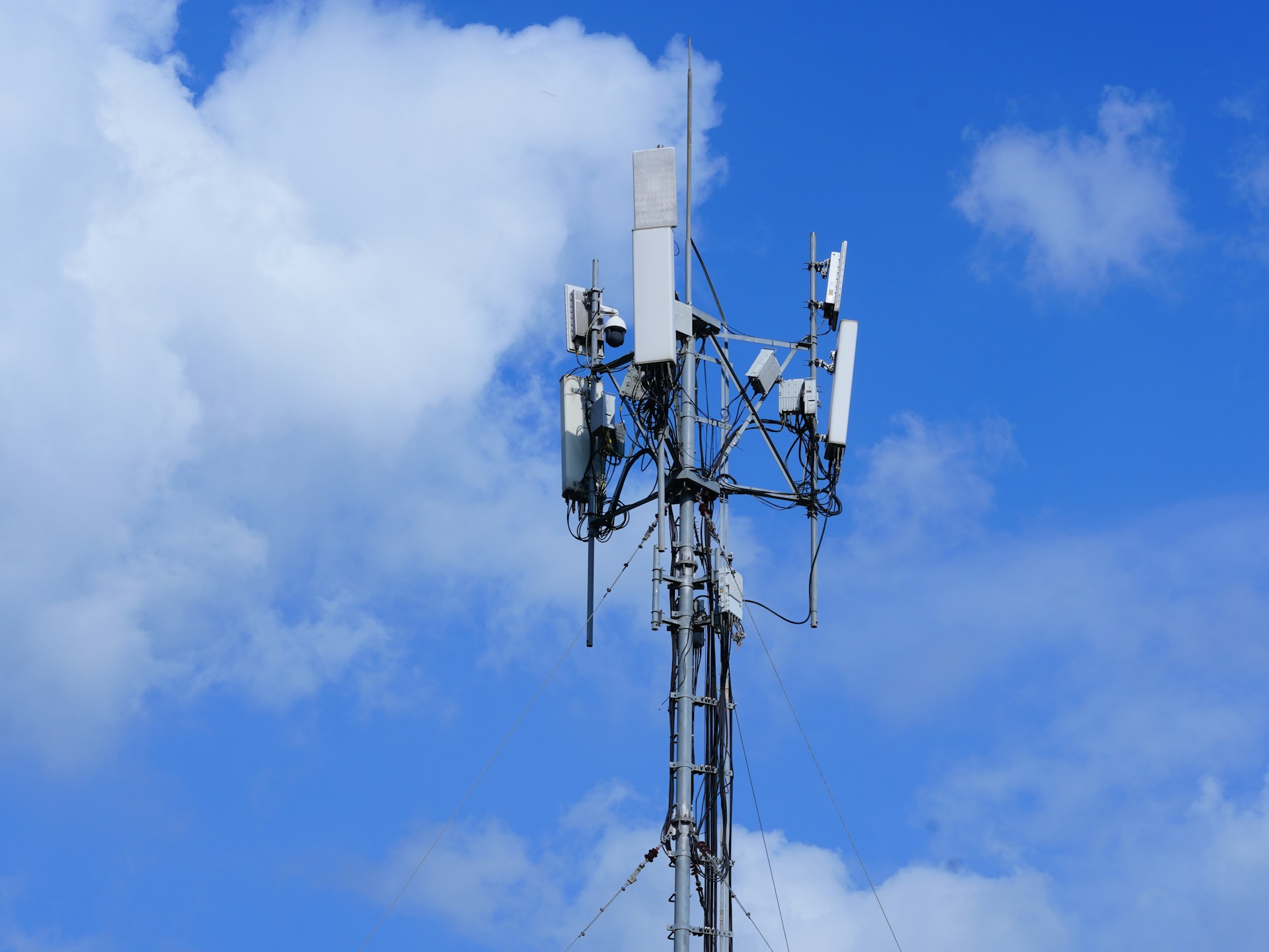 Cell tower with antennas against a cloudy blue sky