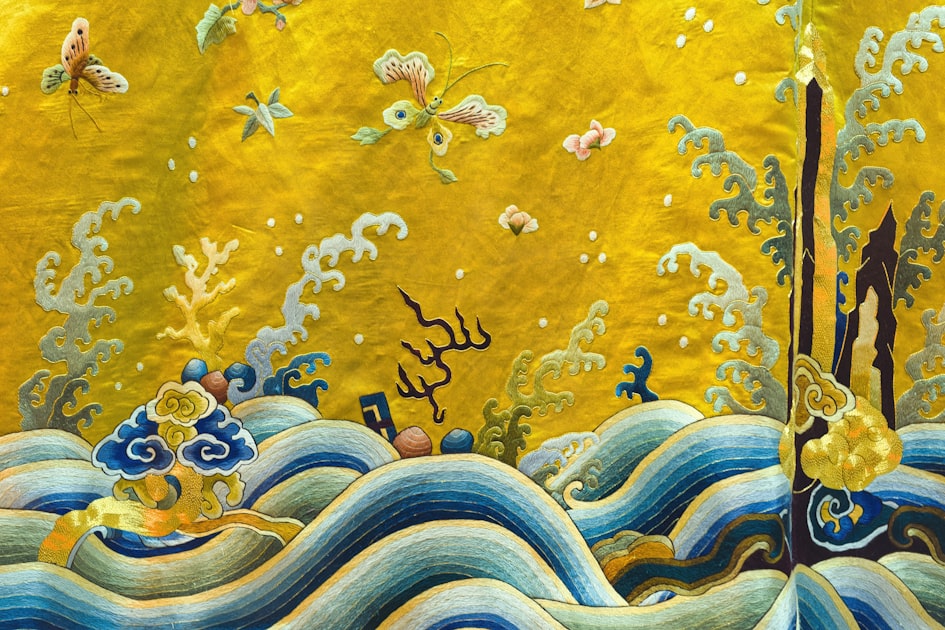 Intricate gold embroidery with waves and floral motifs, representing the technical mastery of Chinese imperial textile traditions