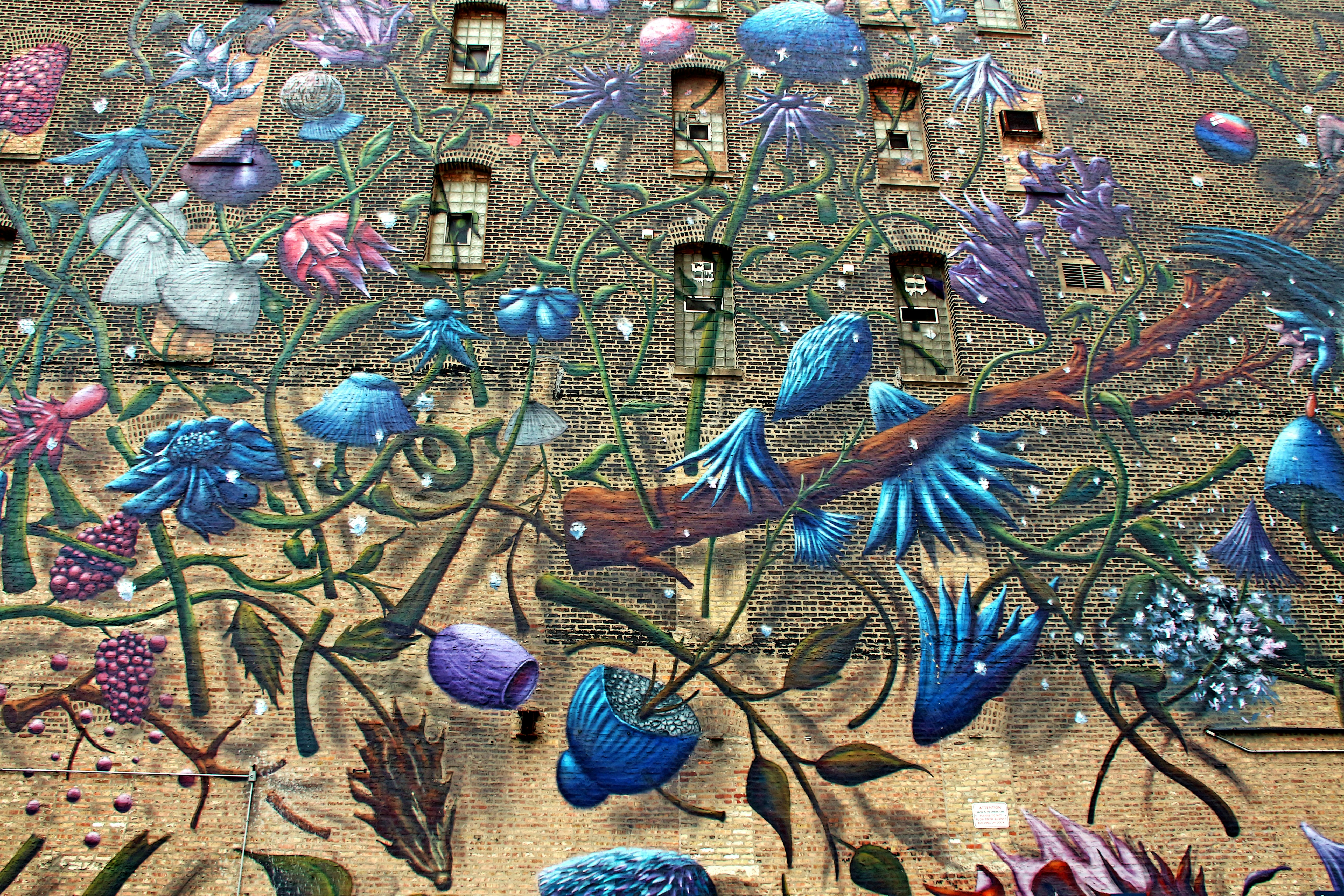 Mural burung dan bunga abstrak berwarna-warni di dinding bata