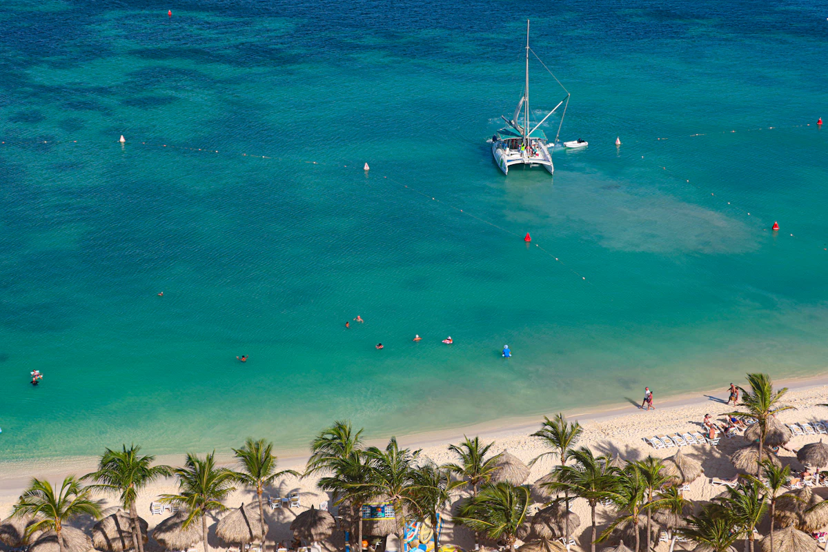 A catamaran sailing in clear turquoise water near a Caribbean beach