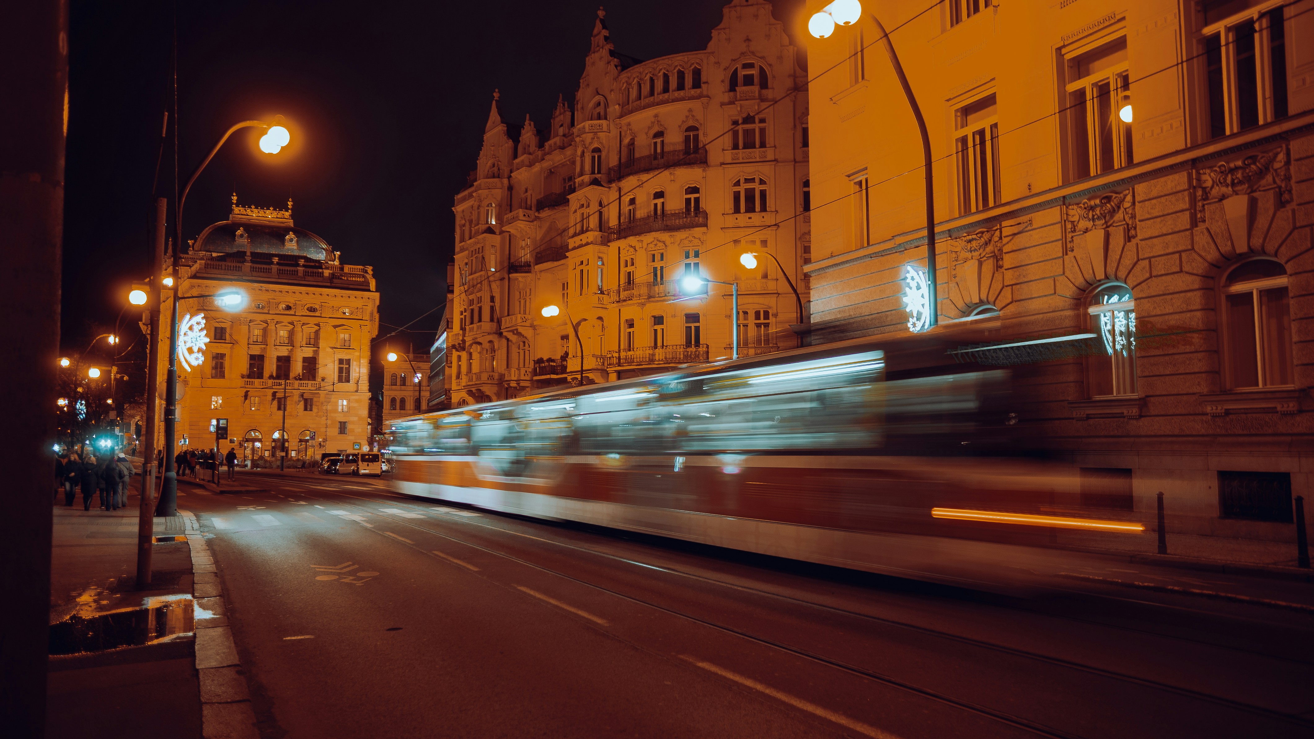 Tram blurred by motion on a city street at night.