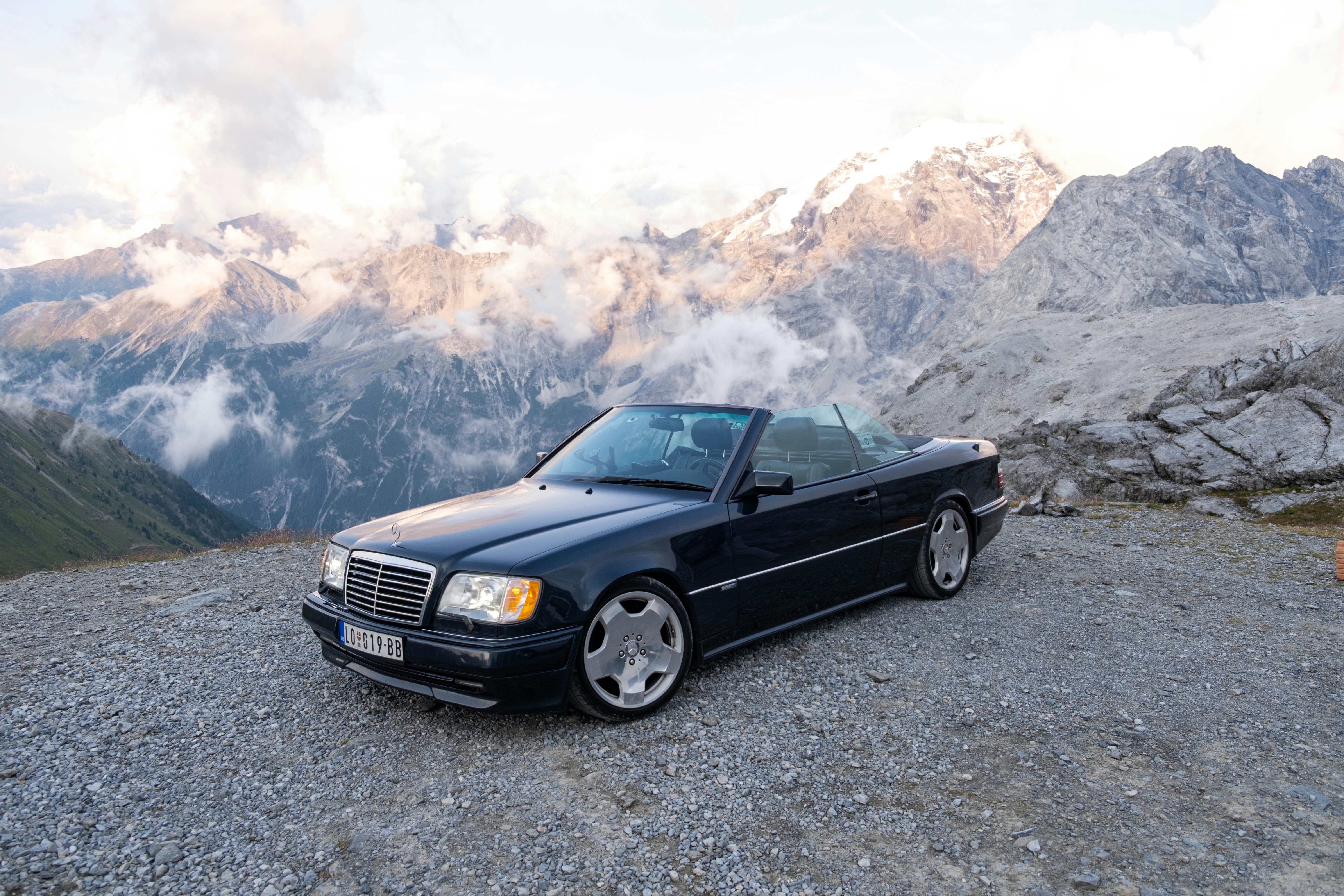 Schwarzes Cabrio, das auf Kies geparkt ist, mit Bergen dahinter