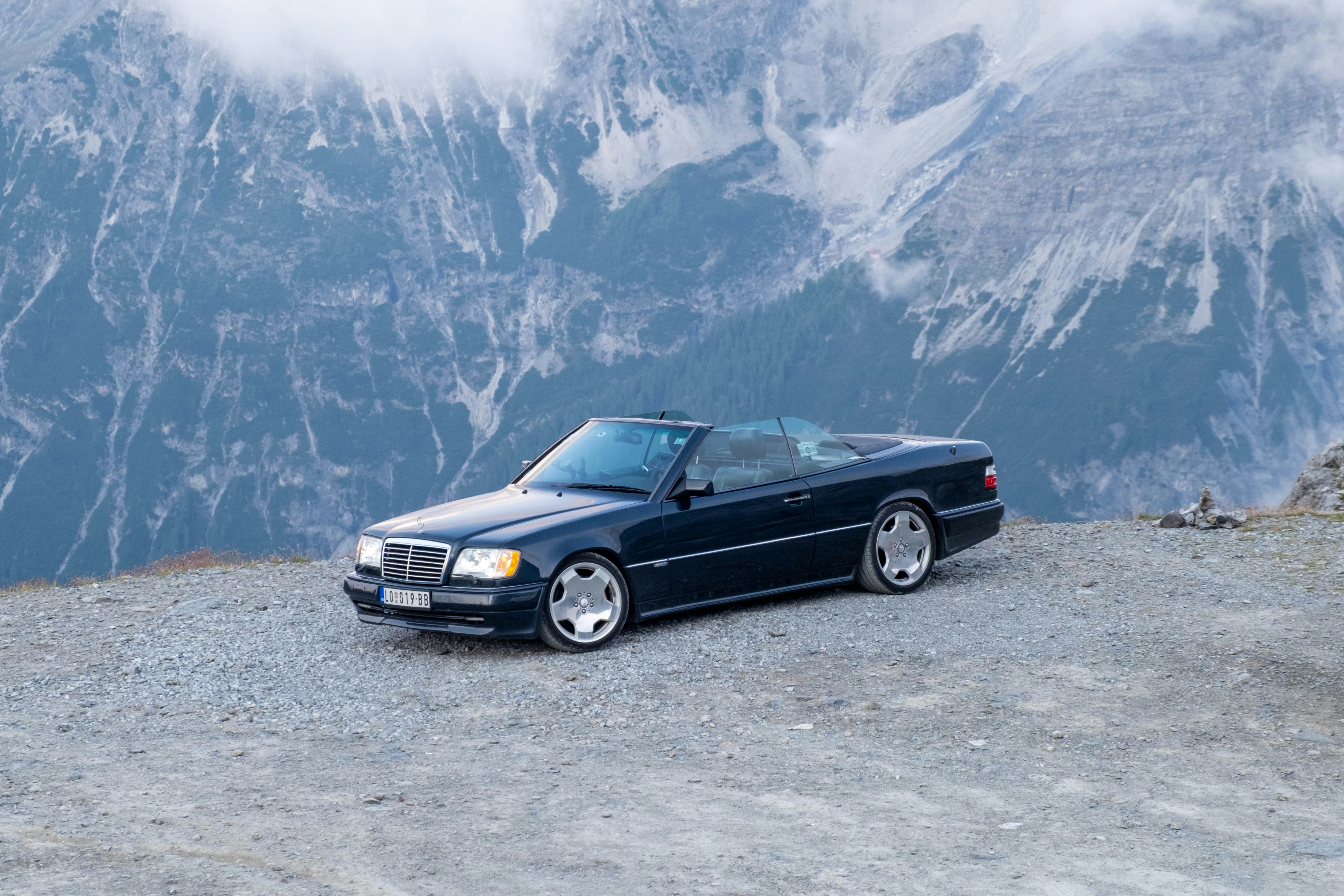 Dunkles Cabriolet auf einer felsigen Bergstraße geparkt.