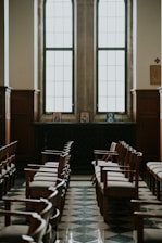 Rows of empty wooden chairs in a church hall.