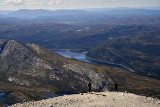 Two hikers on a mountain overlooking a lake.