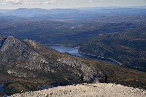 Two hikers on a mountain overlooking a lake.