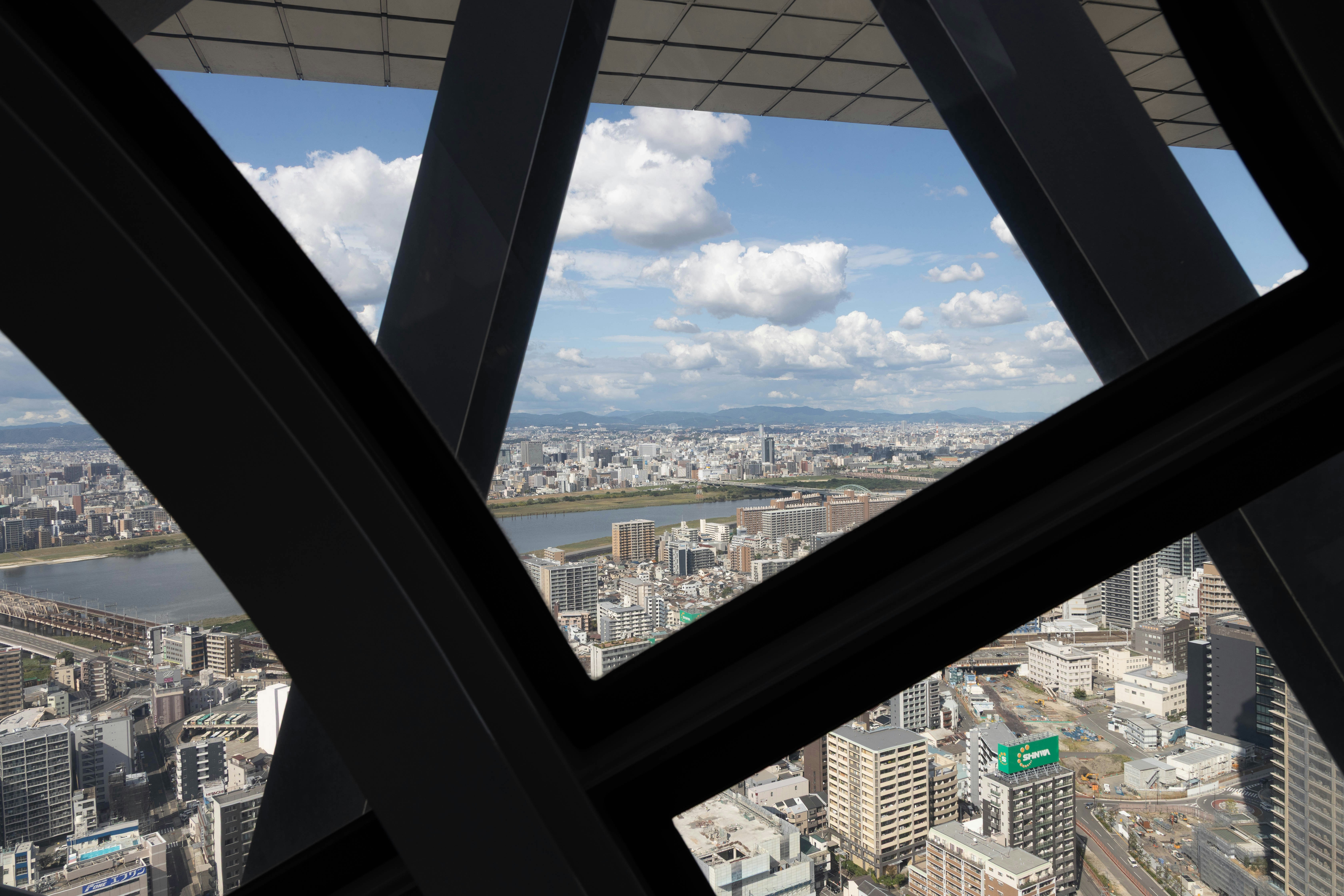 Cityscape seen through dark metal beams under blue sky