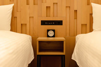 Two beds with a nightstand and clock between them.