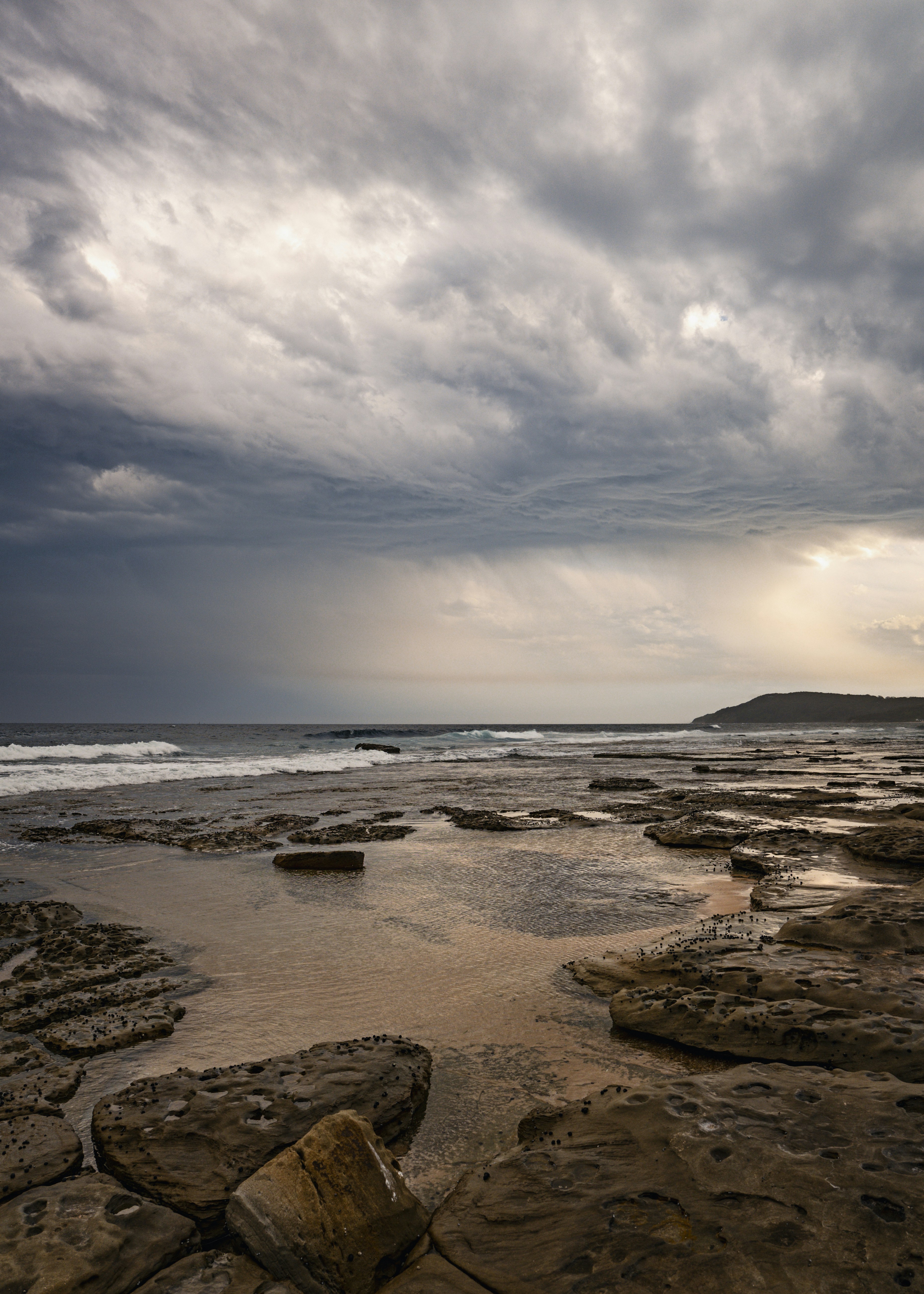 Rocky coastline under dramatic stormy clouds at sunset