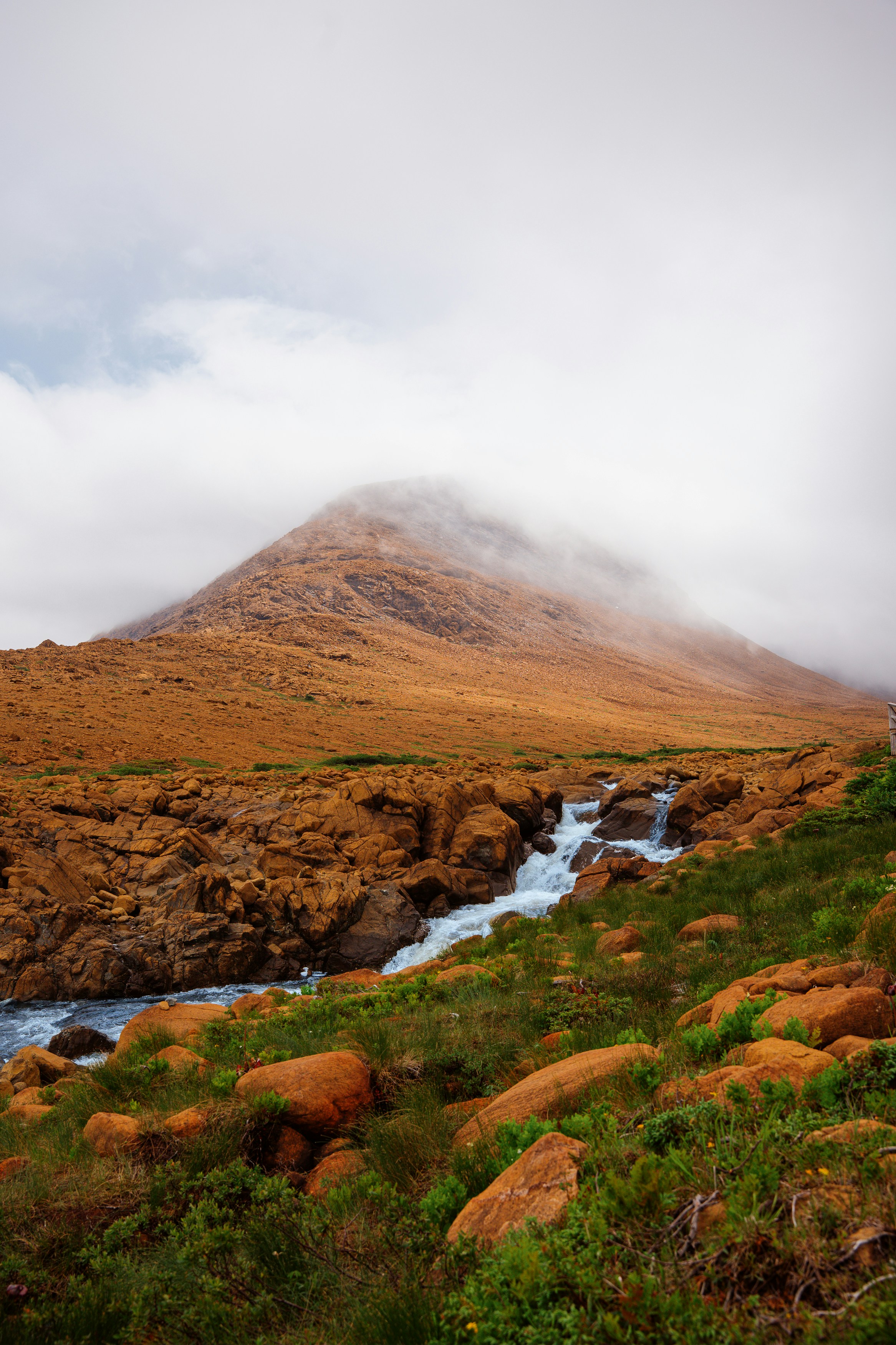 Misty mountain peak above a rocky riverbed