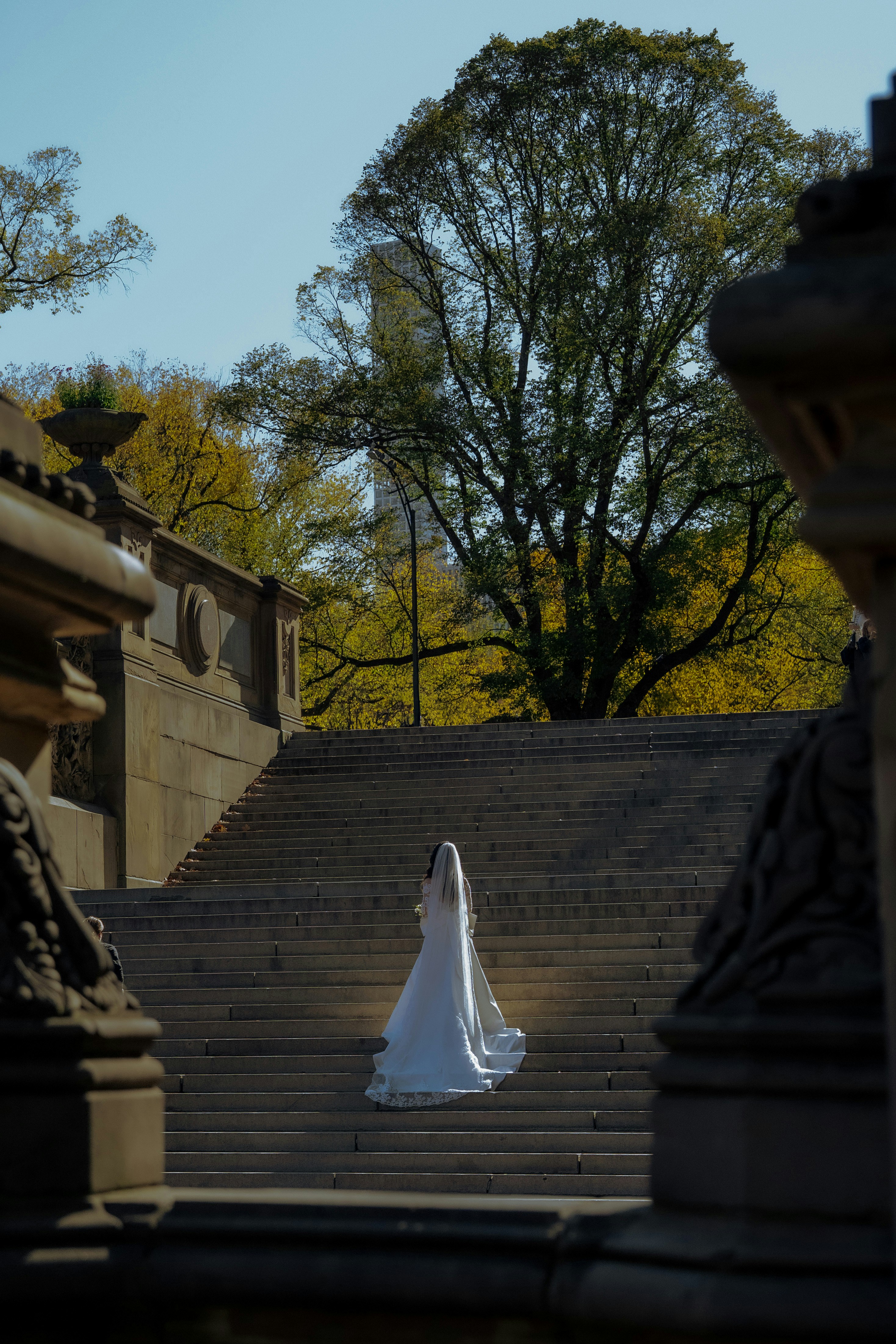 Braut im weißen Kleid steigt steinerne Treppen im Freien hinauf