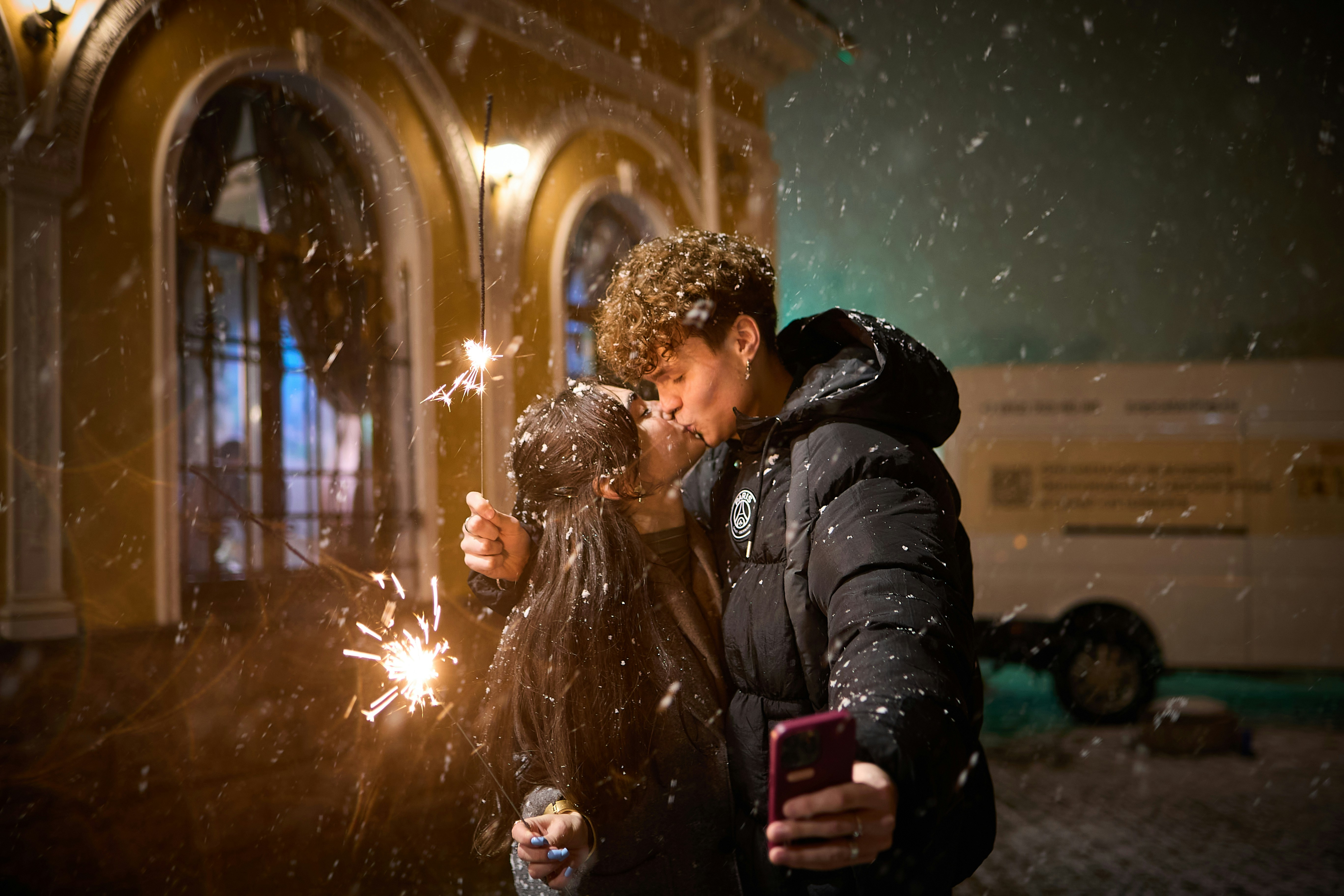 Couple kissing in snow with sparklers
