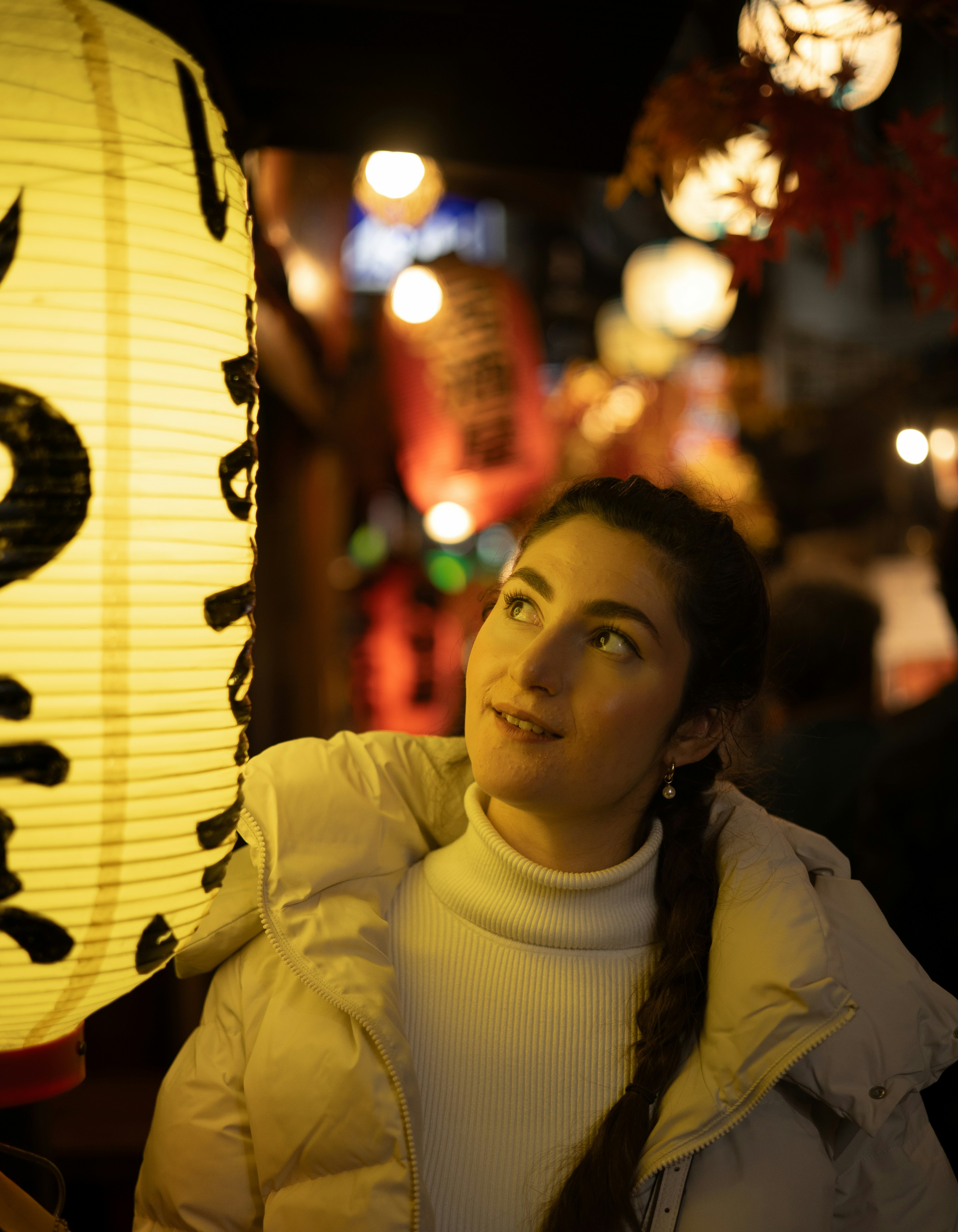 Woman looking at a japanese lantern at night