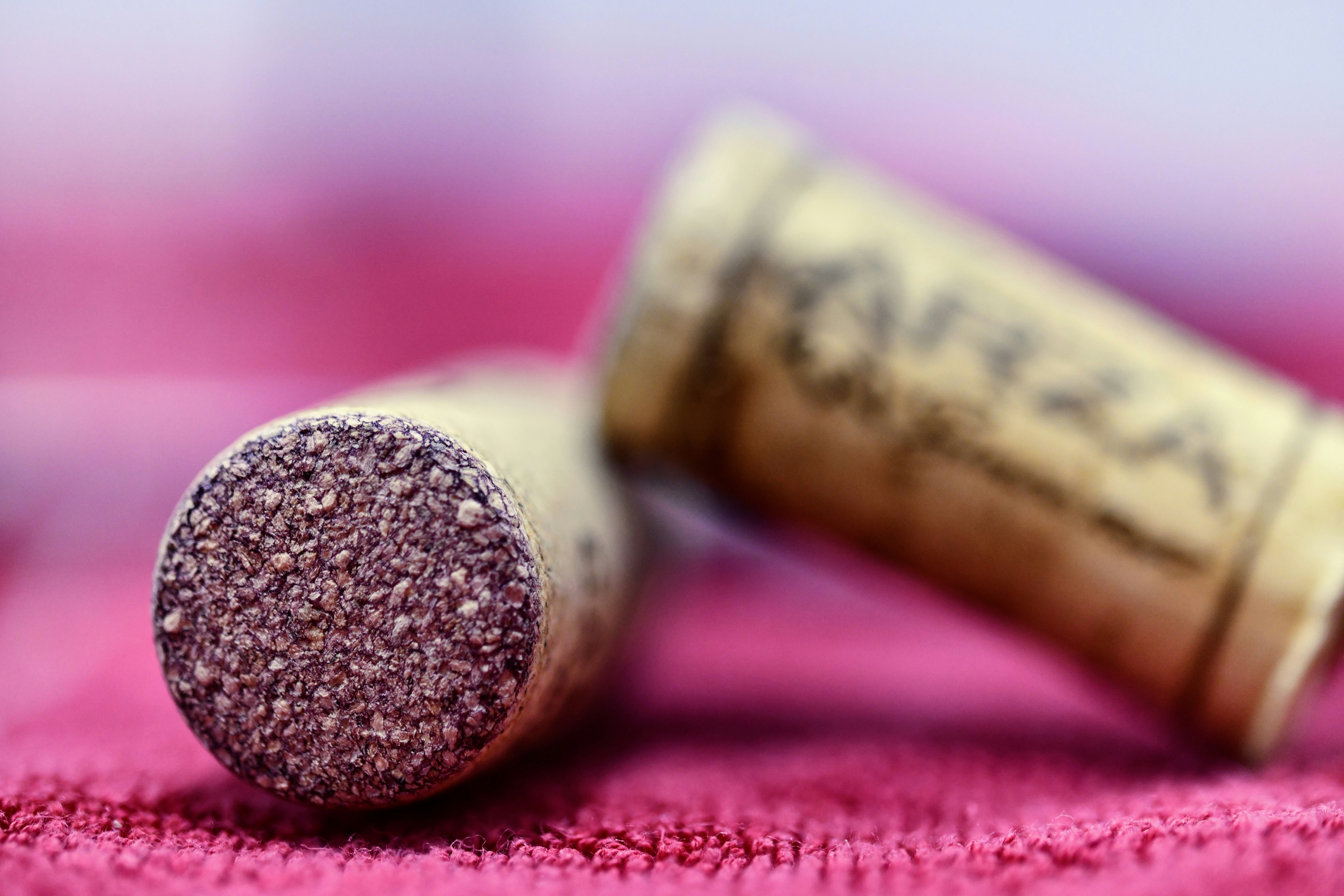 Zwei Weinkorken, die auf einem rosa Tuch ruhen