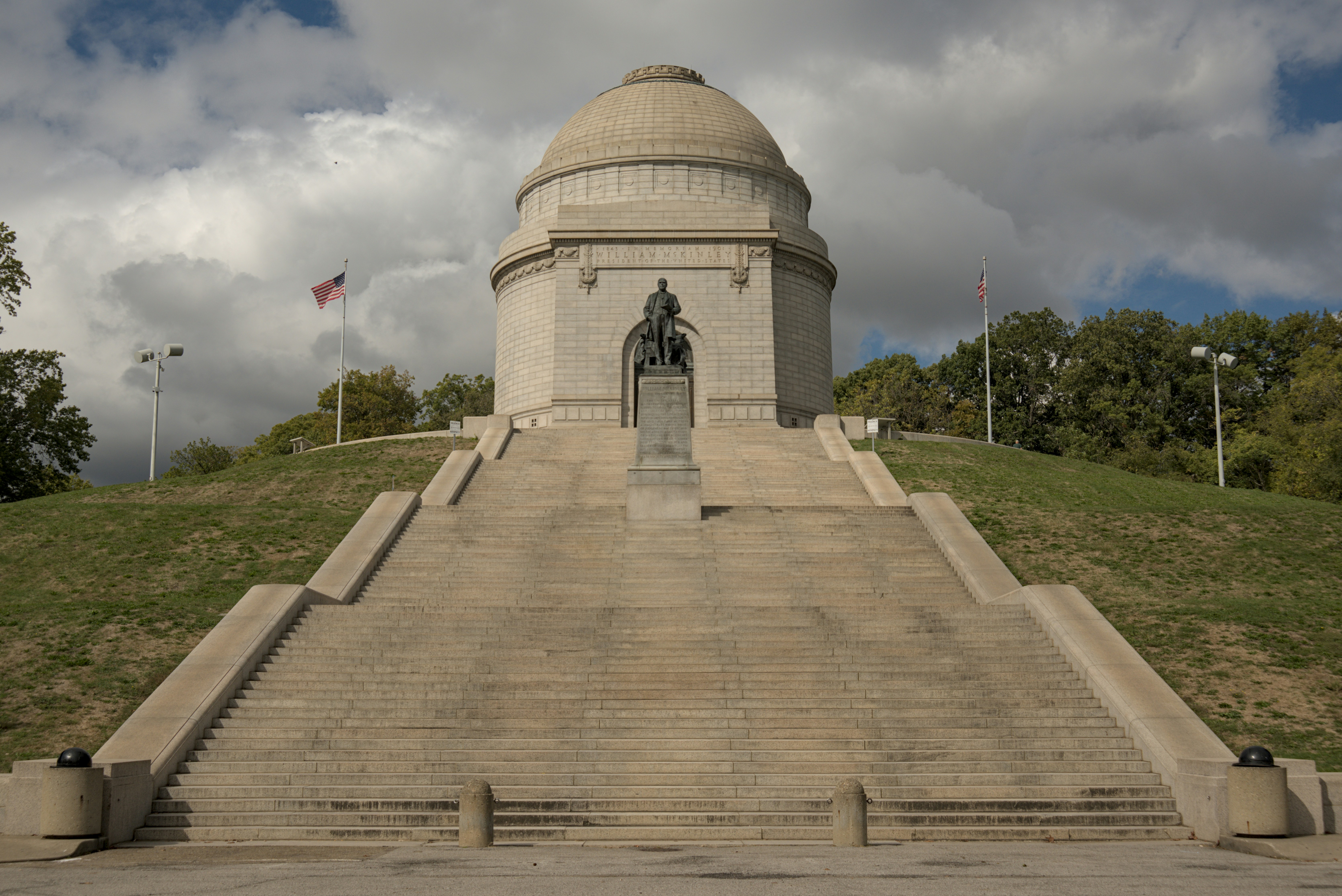 A monument with a statue on a grassy hill
