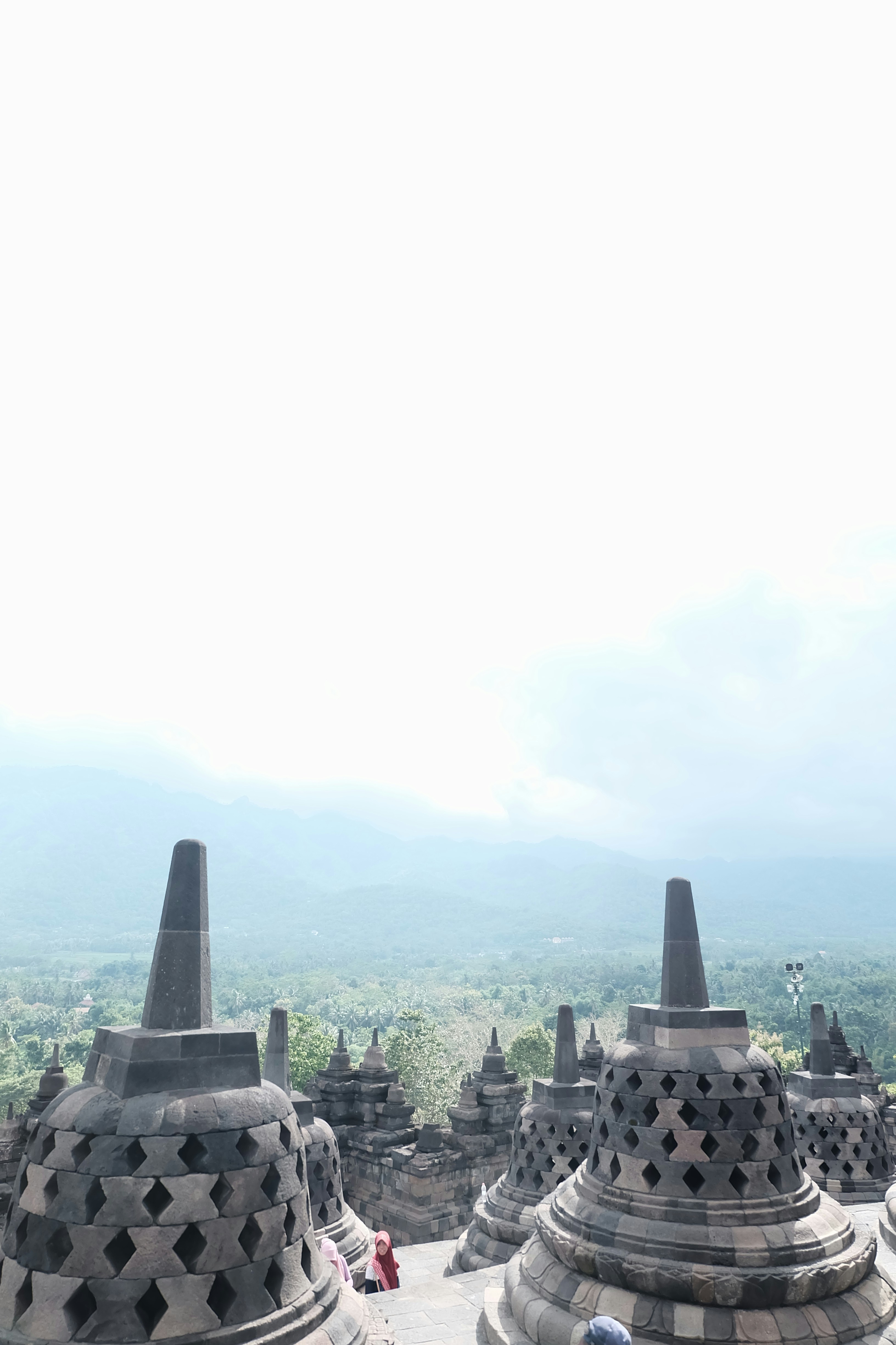 Ancient stupas overlook a lush green landscape at Borobudur. Photo by Ludy Chatry on Unsplash.