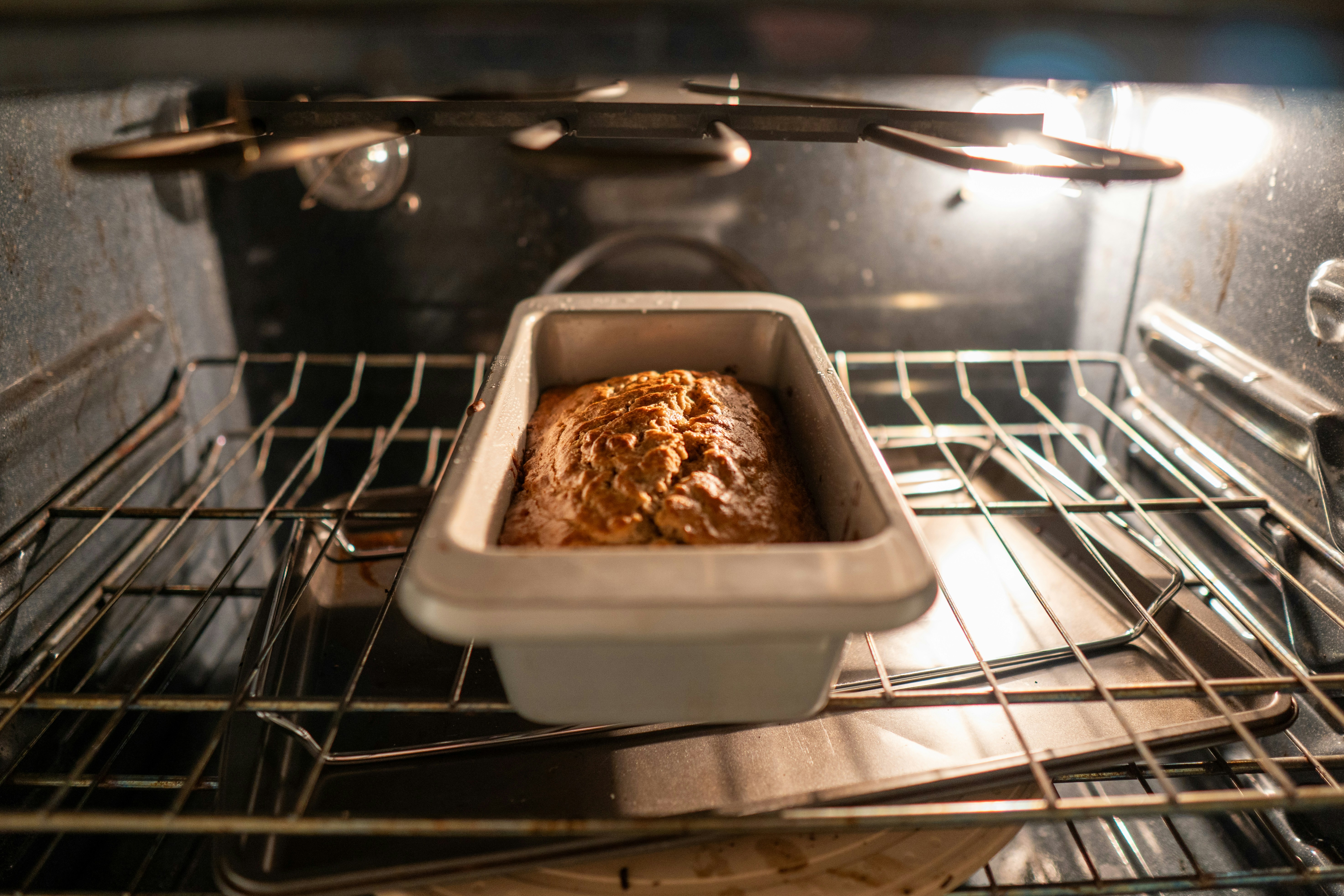 Loaf of bread baking in a metal pan.